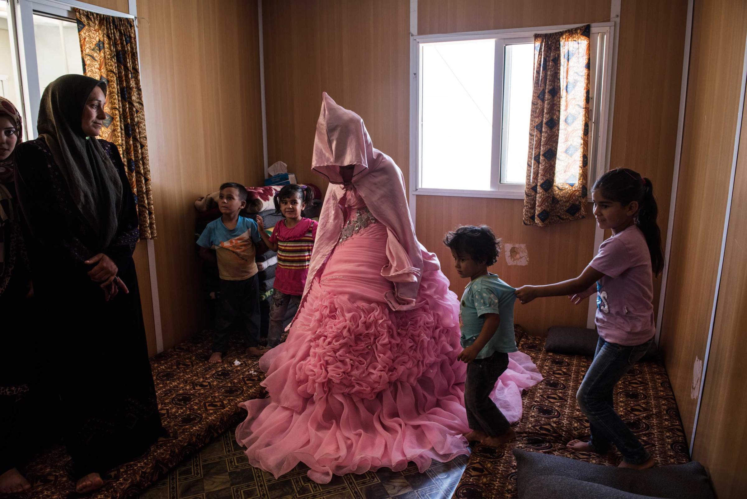 Rahaf Yousef, 13, a Syrian refugee from Daraa, poses for a portrait in her family's trailer as she is surrounded by female relatives on the day of her engagement party at the Zaatari refugee camp in Jordan, Aug. 29, 2014.
