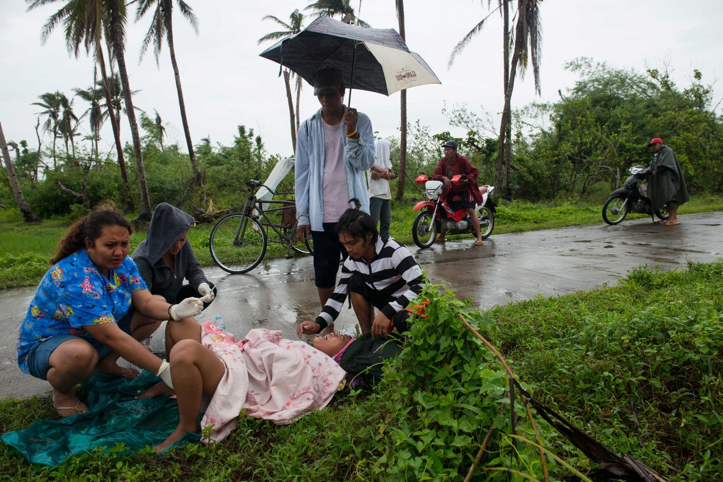 Midwife Norena Malate delivers the baby of Analyn Pesado 18, as Analyn's husband, Ryan Bacate, 21, looks on on the side of the road in Tolosa, outside of Tacloban, in the Philippines, Jan. 11, 2014.