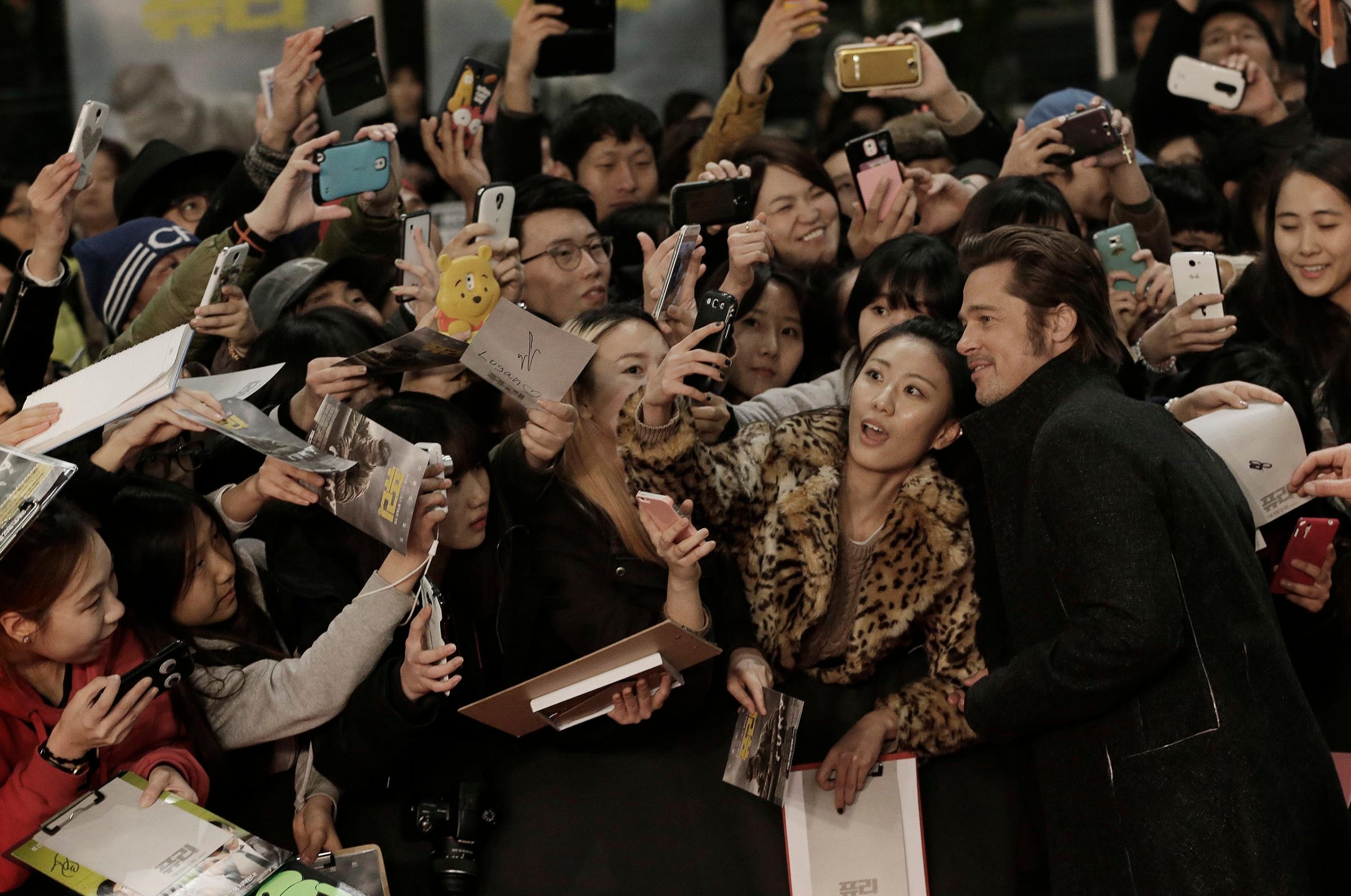Actor Brad Pitt takes pictures with fans during a promotional event for his latest film "Fury" in Seoul, Thursday, Nov. 13, 2014.