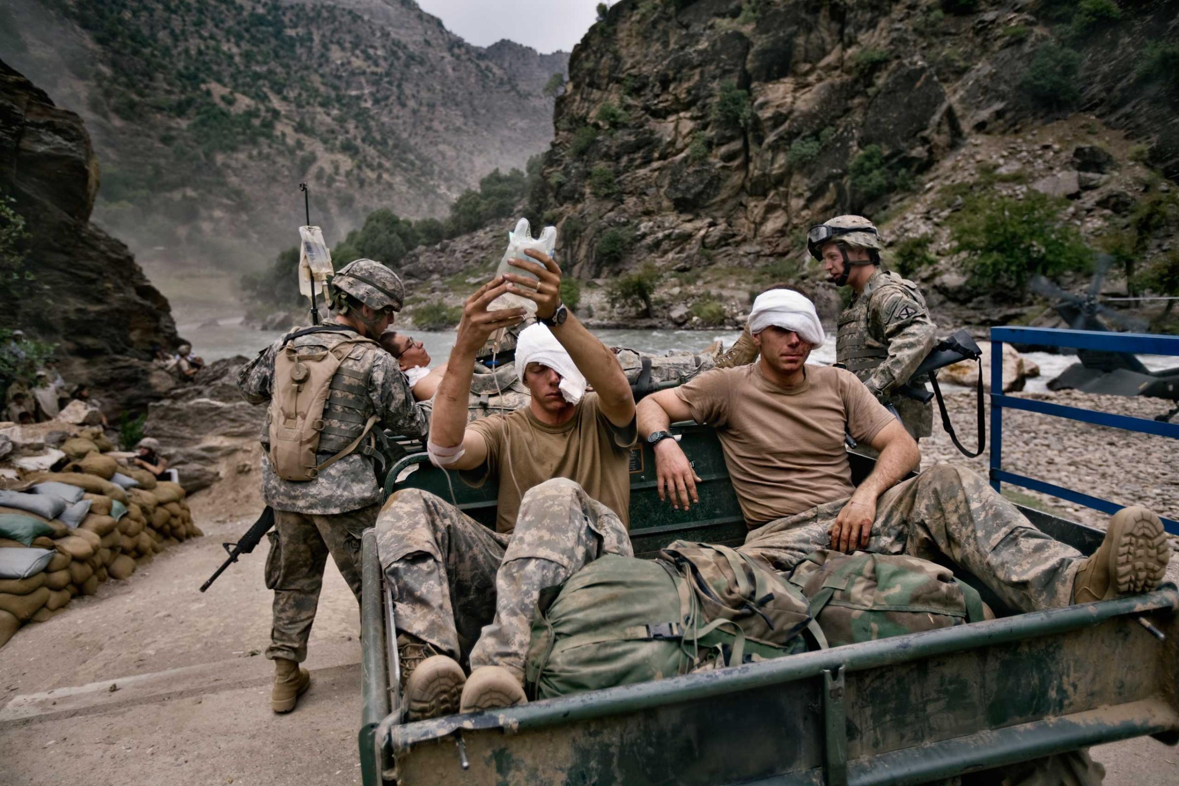AUGUST 2006: Three wounded U.S. Army soldiers from the 10th Mountain Division await evacuation by helicopter from Kamdesh, Nuristan province. They were ambushed and suffered wounds to their eyes and foreheads.  (Photo by Robert Nickelsberg)