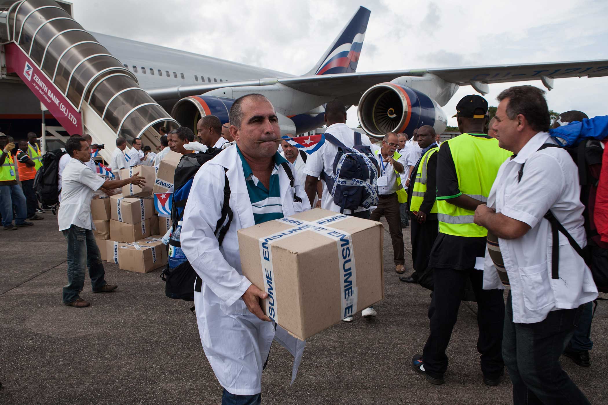 The first members of a team of 165 Cuban doctors and health workers unload boxes of medicines and medical material from a plane upon their arrival at Freetown's airport to help the fight against Ebola in Sierra Leone, on October 2, 2014. (Florian Plaucheur—AFP/Getty Images)