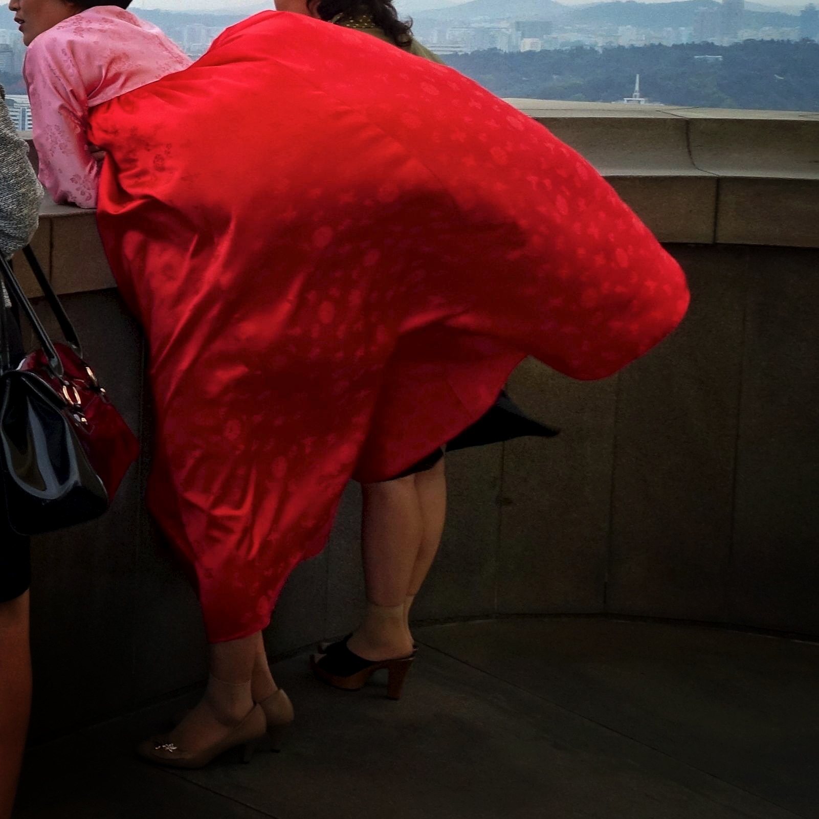 A woman's traditional dress billows in the strong breeze on top of Juche Tower in Pyongyang.