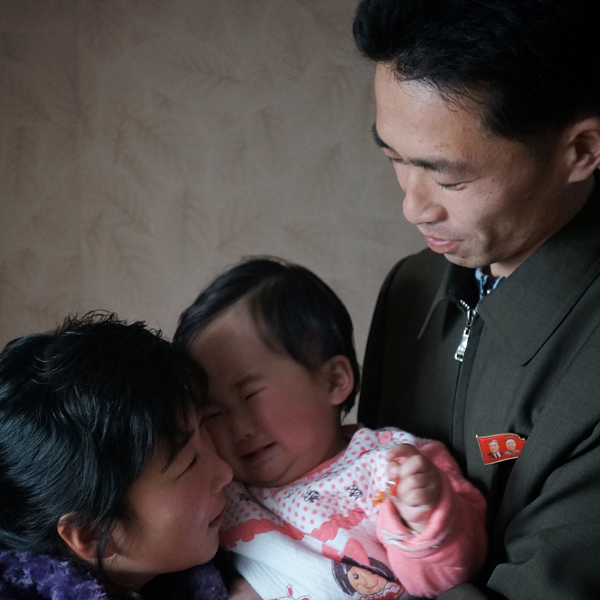A newlywed North Korean couple comfort their crying baby in their Pyongyang home.