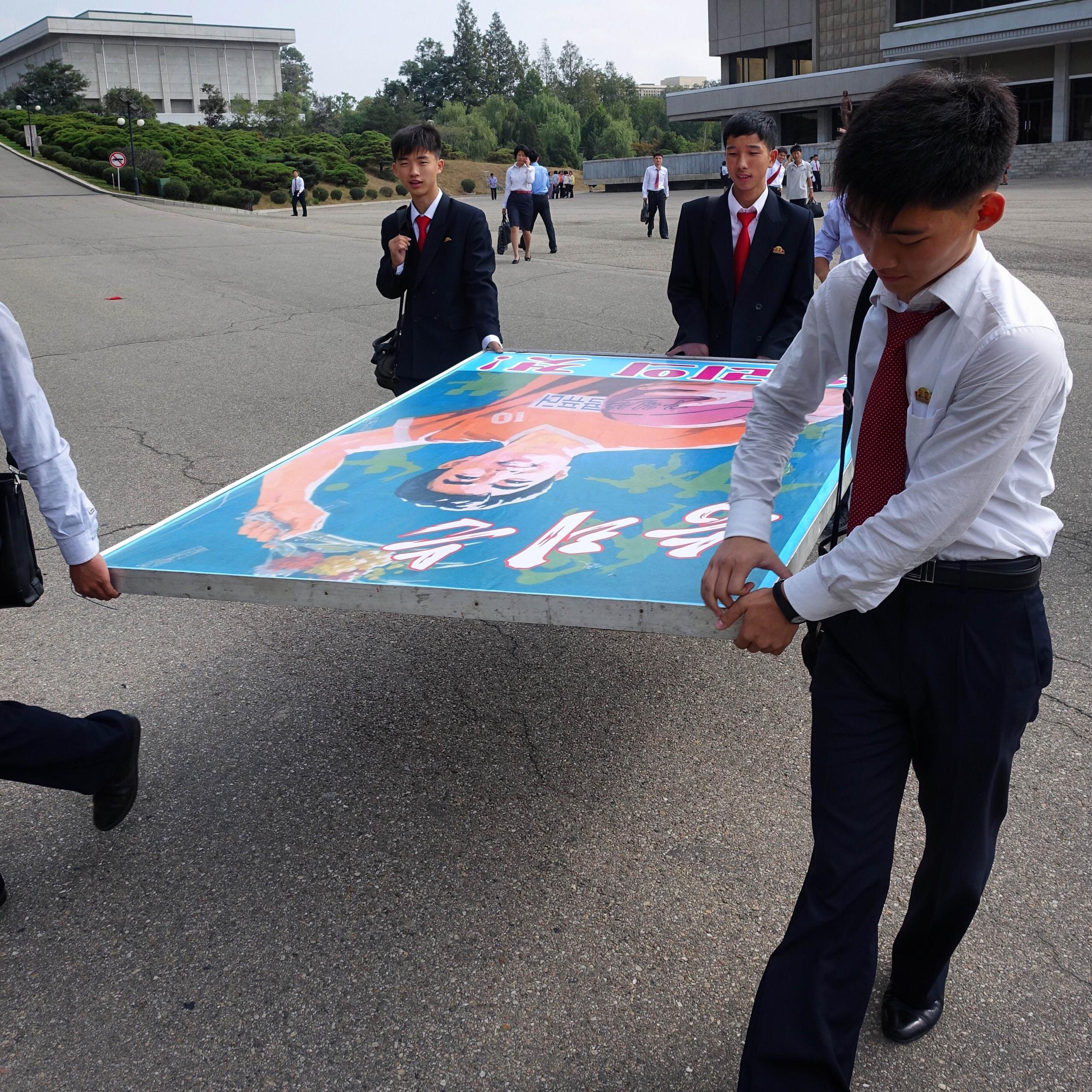 Computer Science students of Kim Il Sung University carry a poster board that says "Victory is Ours!" during the school's 78th anniversary celebrations.