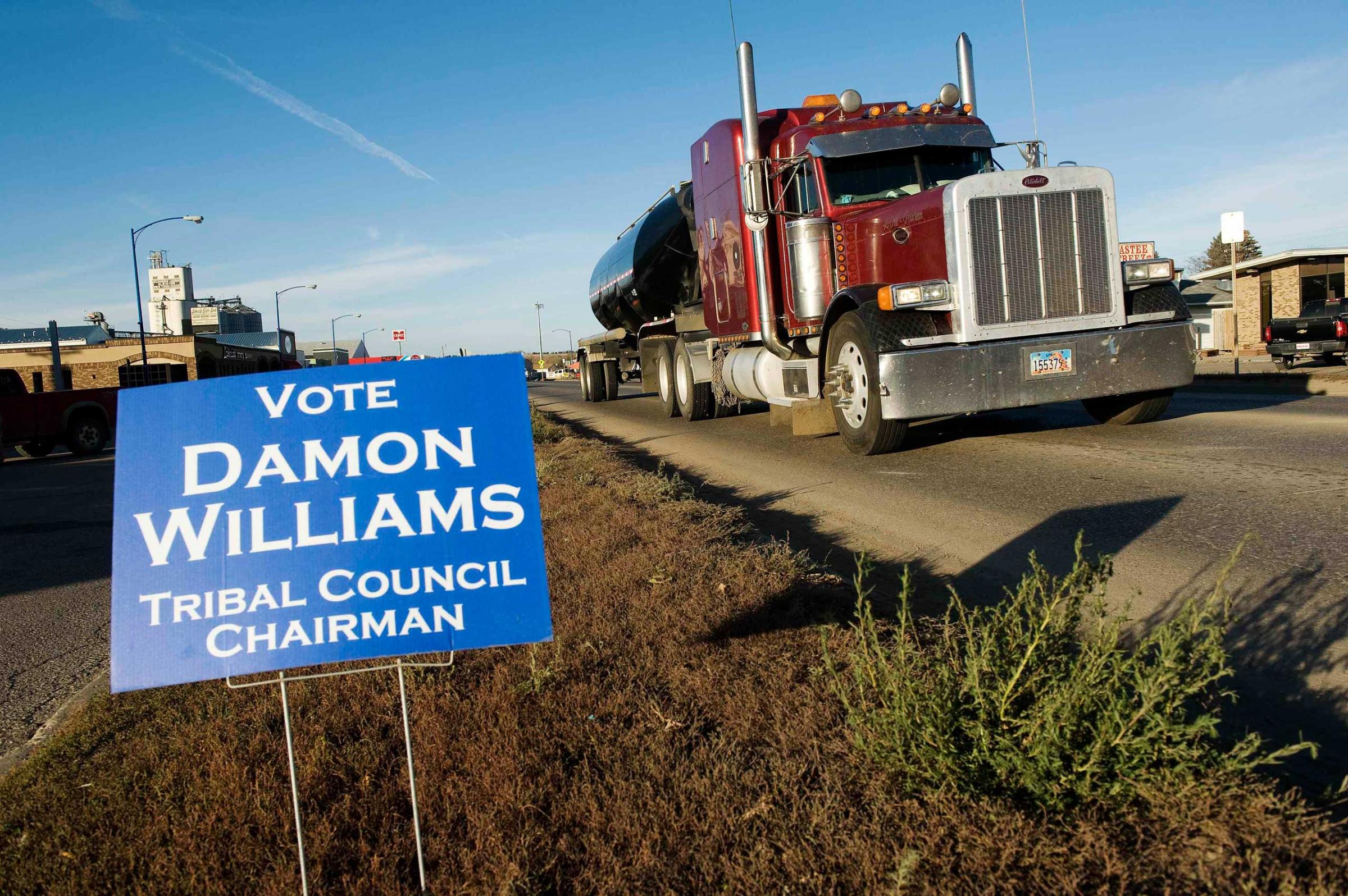 Oil field traffic passes a campaign sign for Three Affiliated Tribes council chairman candidate Williams in New Town on the Fort Berthold Reservation in North Dakota