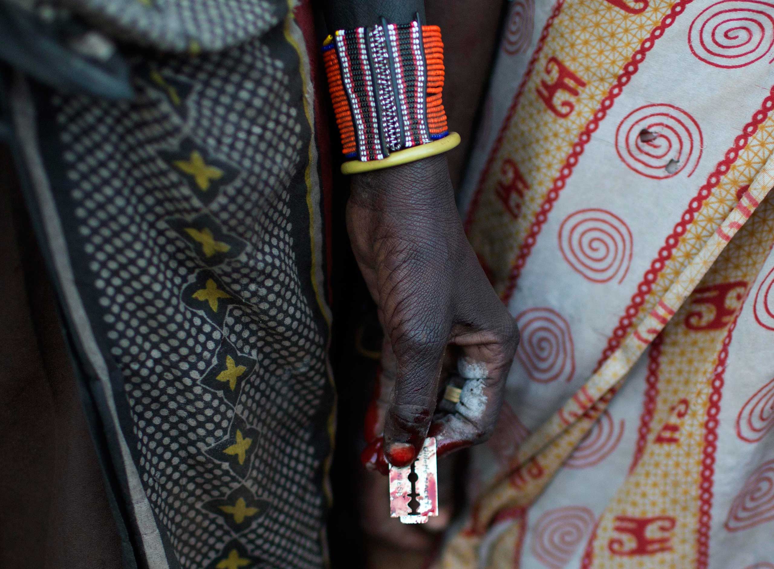 A Pokot woman holds a razor blade after performing a circumcision on four girls in a village about 80 kilometres from the town of Marigat in Baringo County