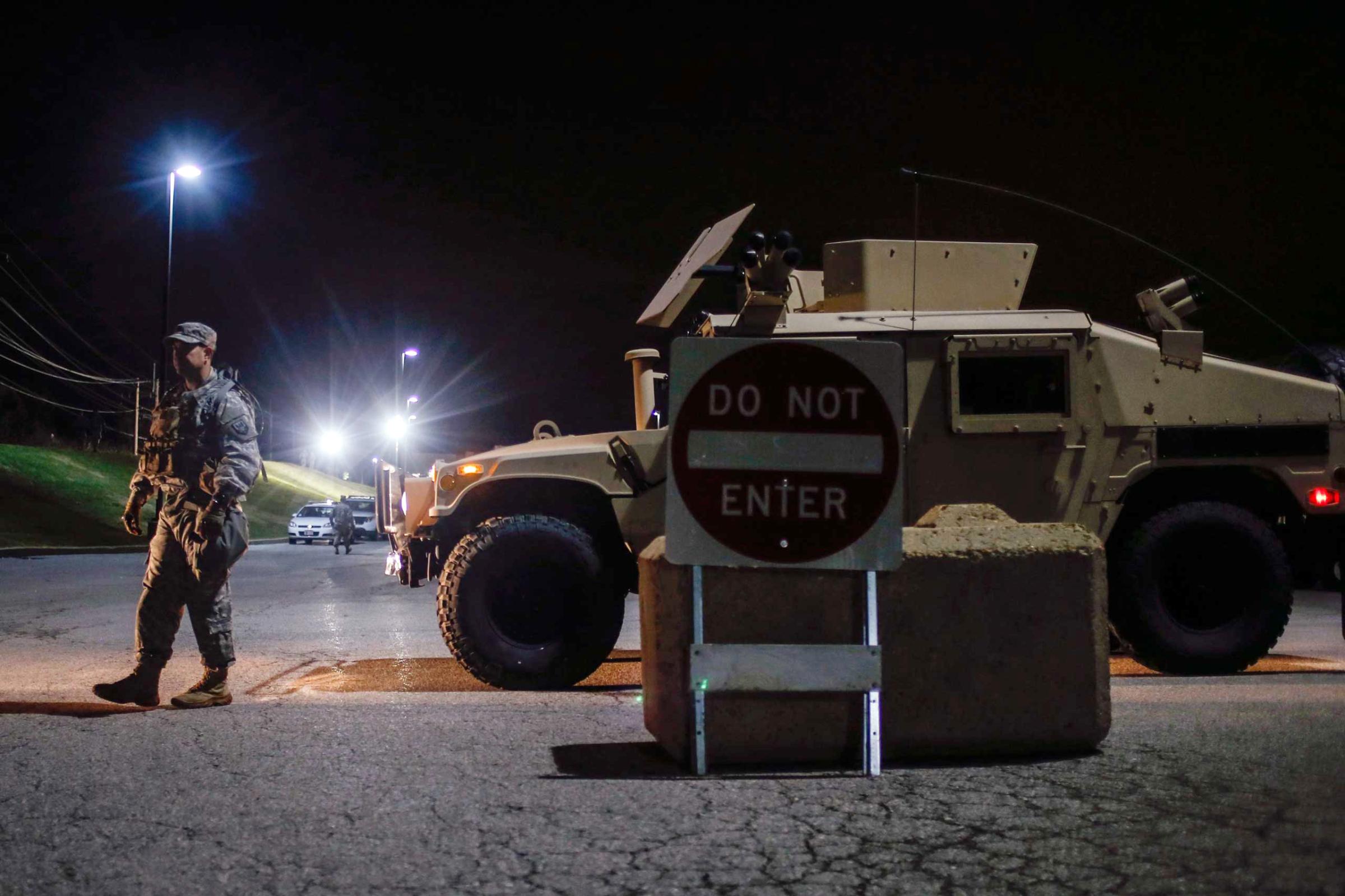 Member of the National Guard stands along a parked military vehicle in the back of a shopping center in Ferguson, Missouri