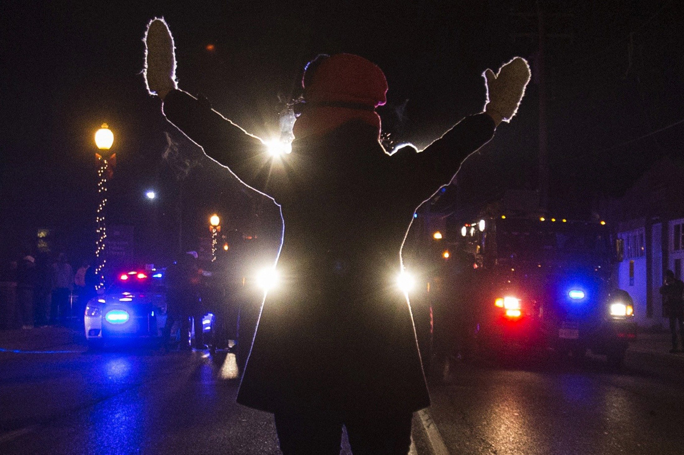 A female protester raises her hands while blocking police cars in Ferguson