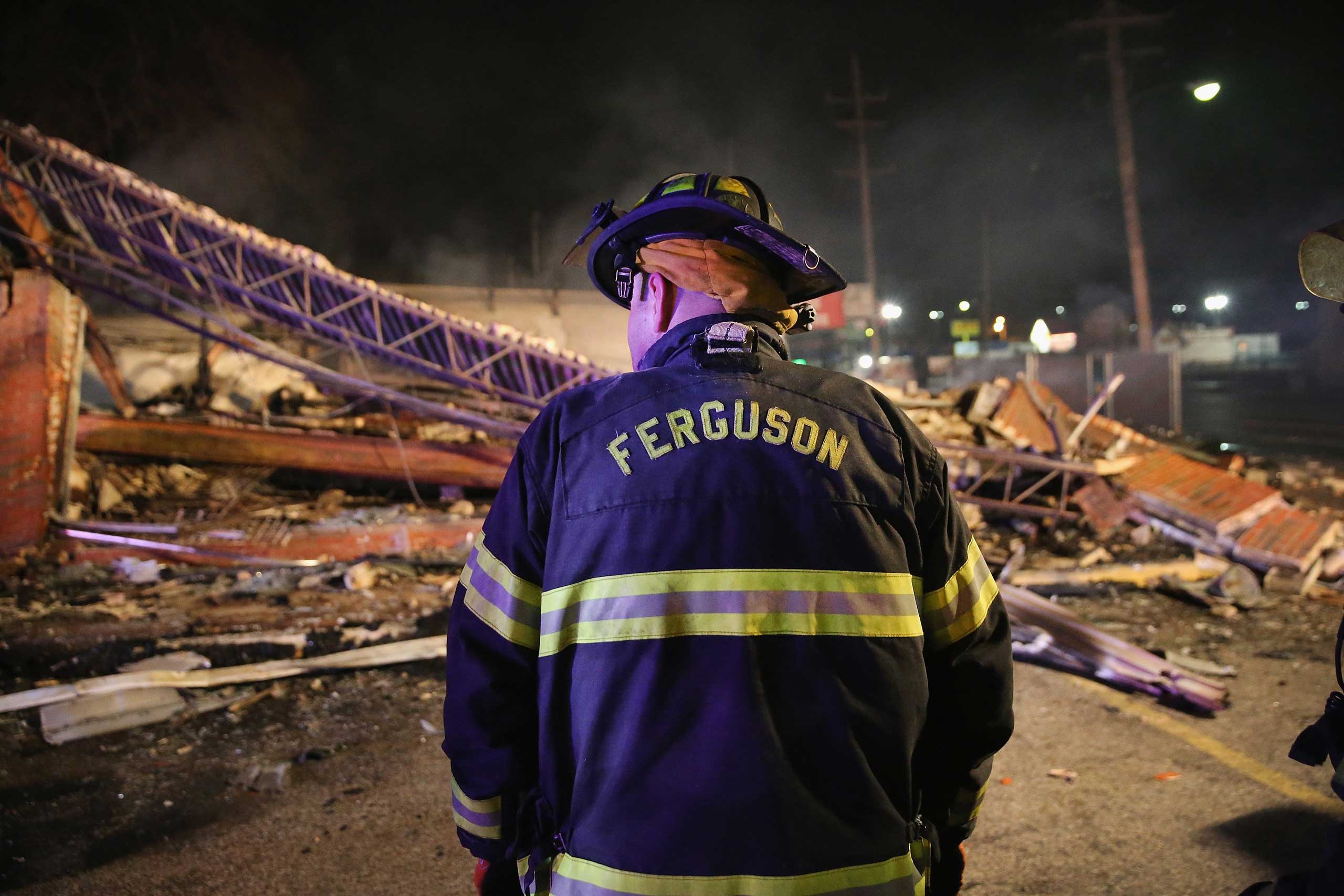 A Ferguson firefighter surveys rubble at a strip mall that was set on fire when rioting erupted following the grand jury announcement in the Michael Brown case on Nov. 25, 2014 in Ferguson, Mo.
