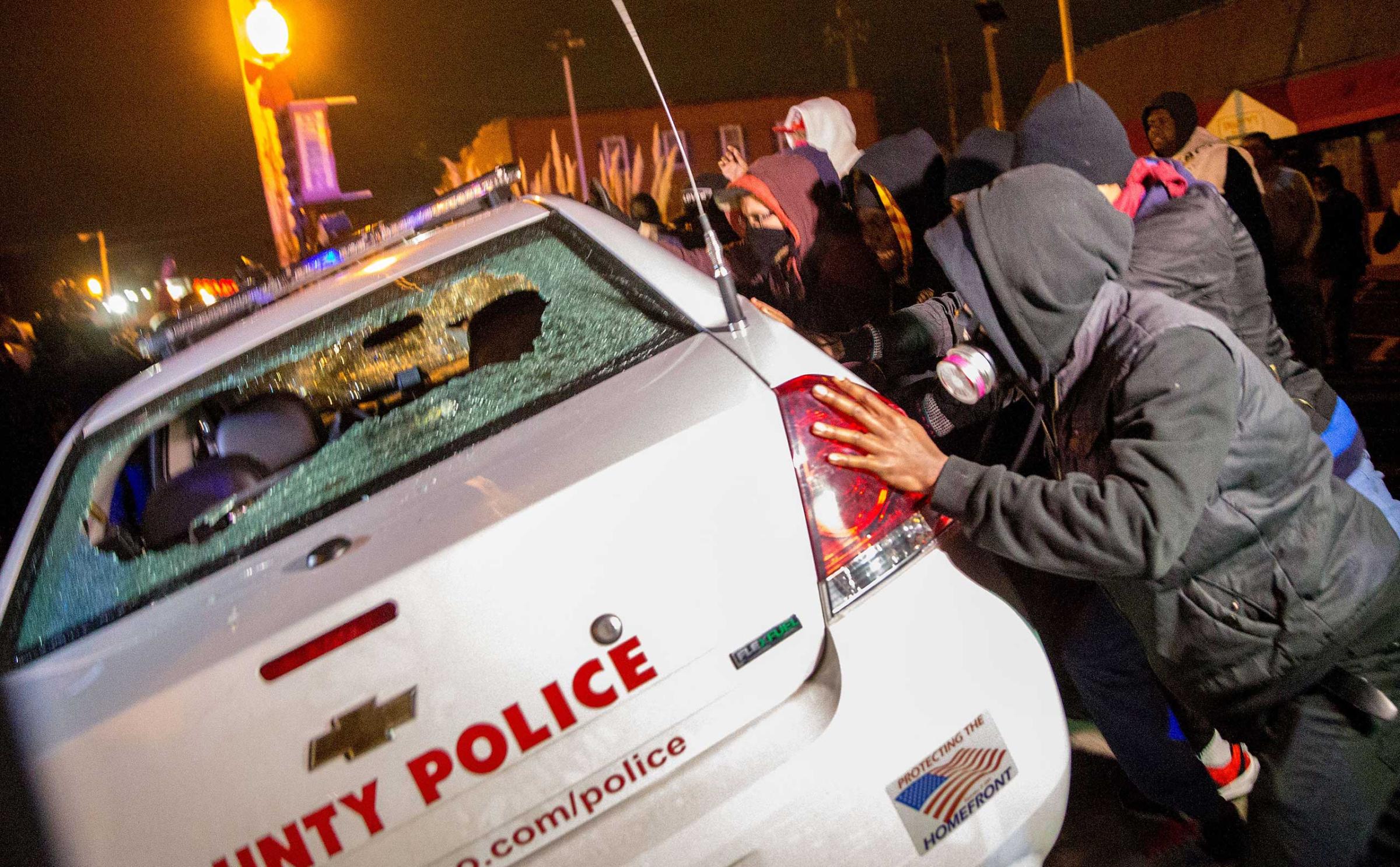 Demonstrators attempt to push over a police car in Ferguson, Mo. on Nov, 24, 2014.