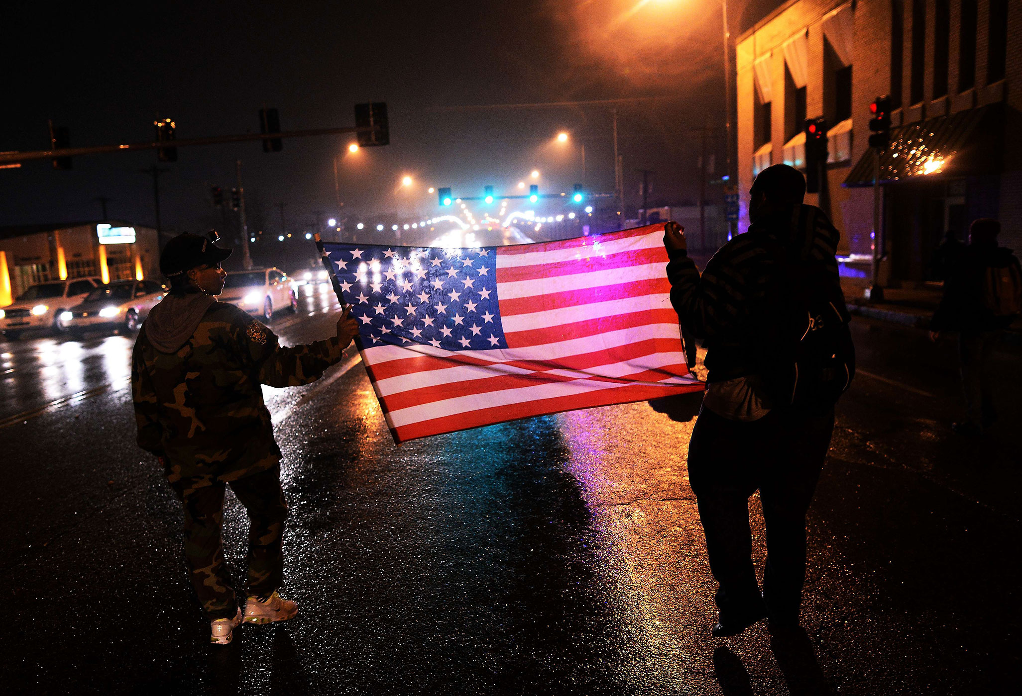 Two demonstrators march with a U.S. flag in St. Louis on Nov. 23, 2014, to protest the death of 18-year-old Michael Brown (Jewel Samad—AFP/Getty Images)