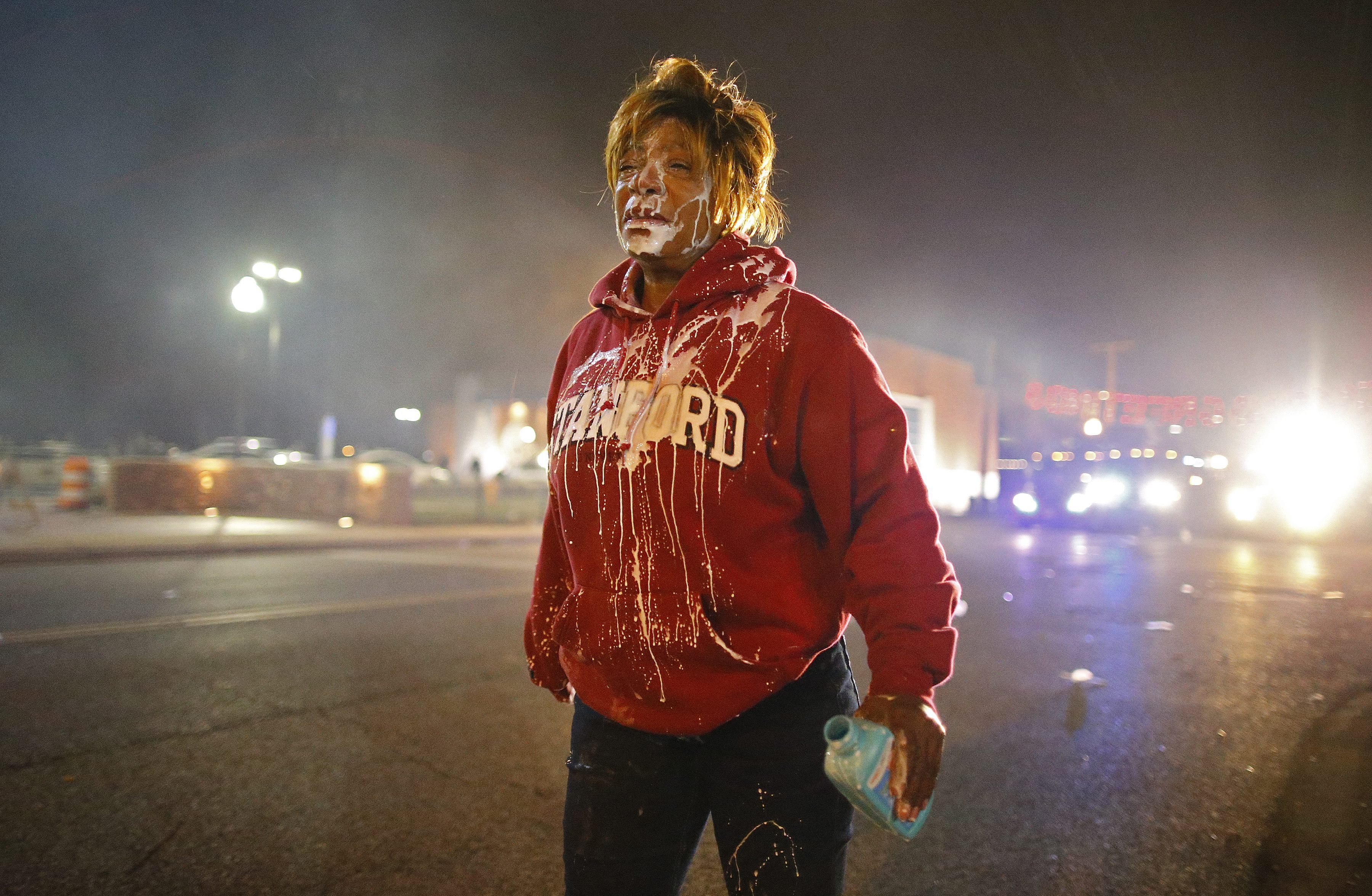 A demonstrator walks down the street after getting tear gas in her face and attempting to cleanse her eyes in Ferguson, Mo. on Nov. 24, 2014.