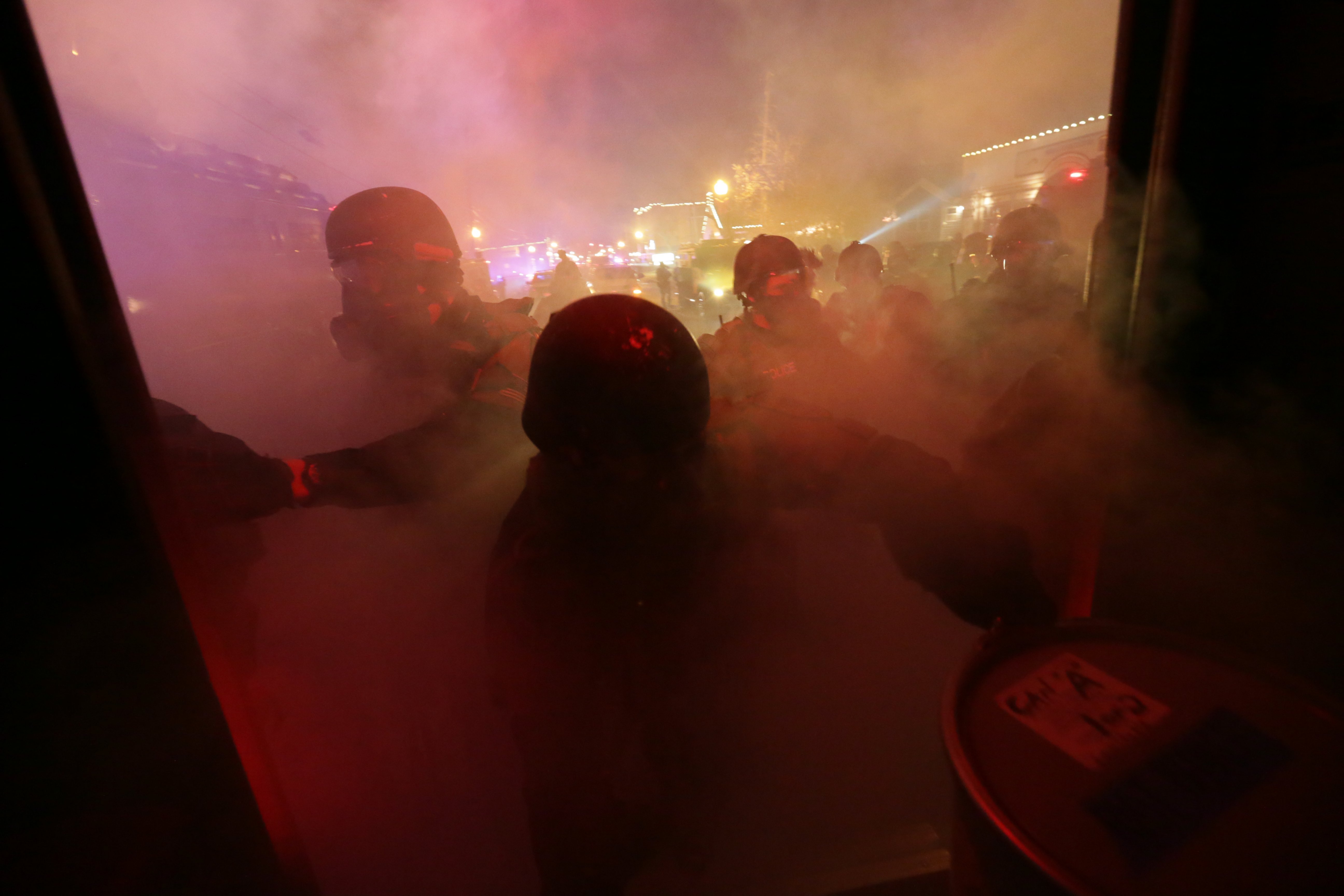 St. Louis County Police tactical team members  open their reserve supply of tear gas to be fired as they take cover behind an armored truck on S. Florissant Avenue in Ferguson, Mo. on Nov. 24, 2014.