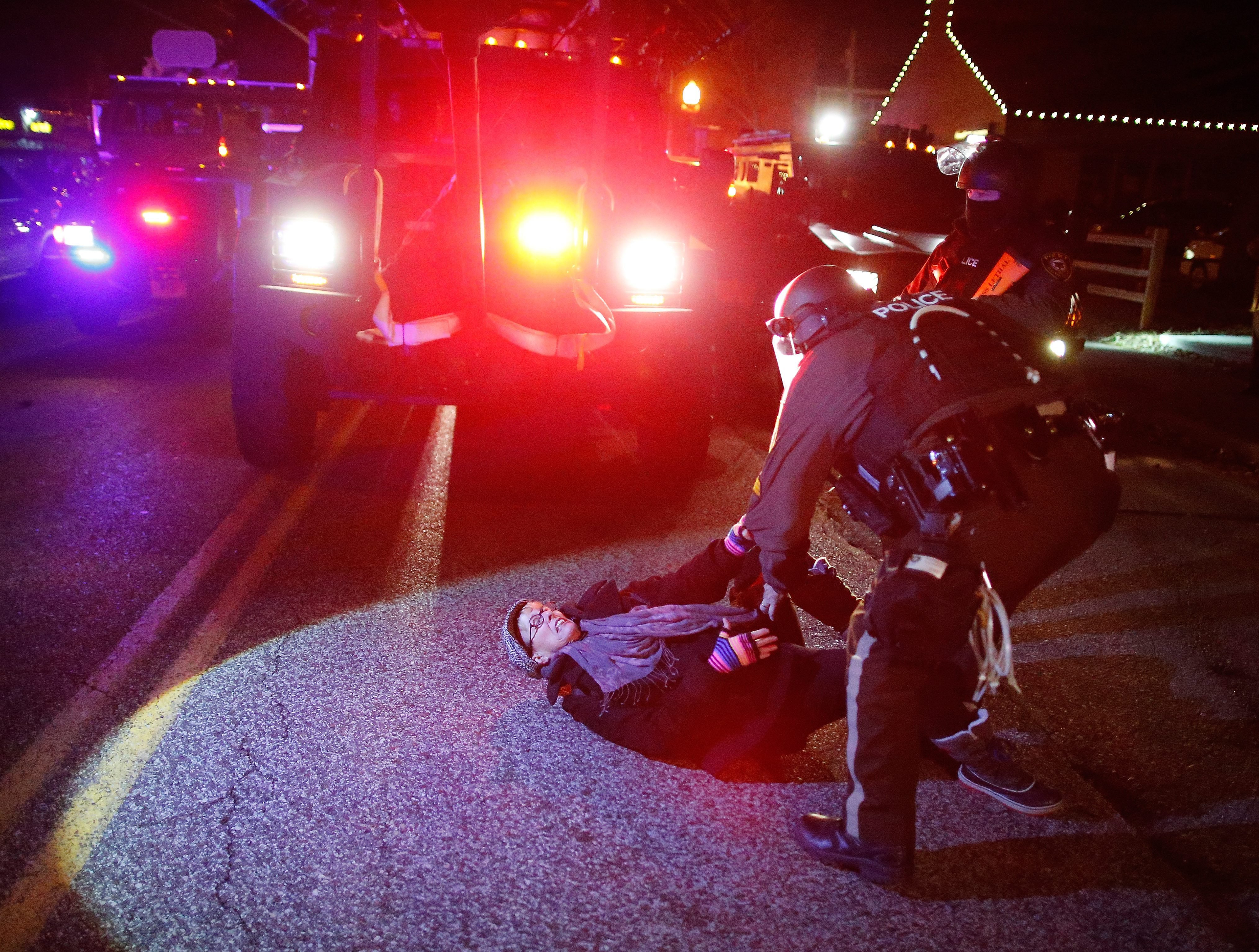Police in riot gear tangle with a woman in front of emergency vehicles in Ferguson Mo. on Nov. 24, 2014.
