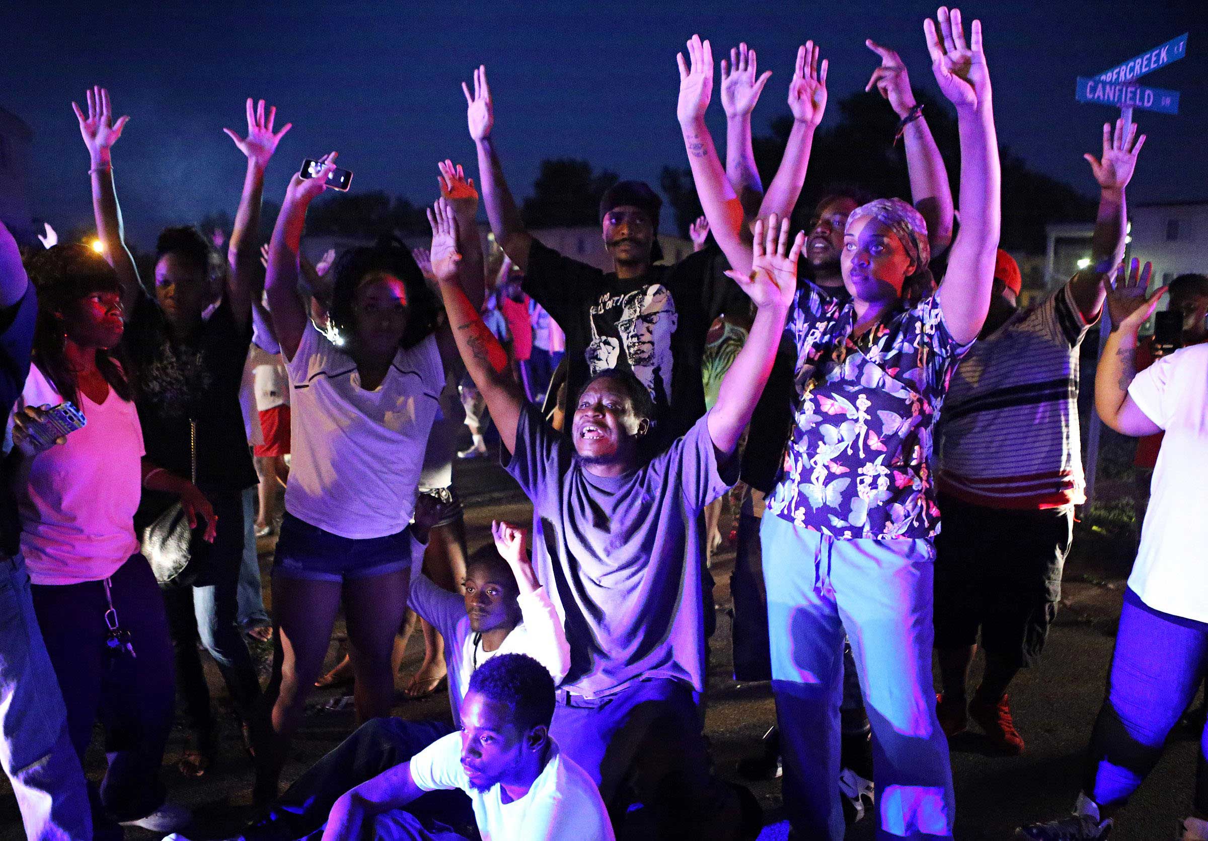 Aug. 9, 2014. A crowd gathers near the scene where 18-year-old Michael Brown was fatally shot by police in Ferguson, Mo., near St. Louis on Saturday. A spokesman with the St. Louis County Police Department confirmed a Ferguson police officer shot the man. The spokesman didnt give the reason for the shooting, nor provide the officers name or race.