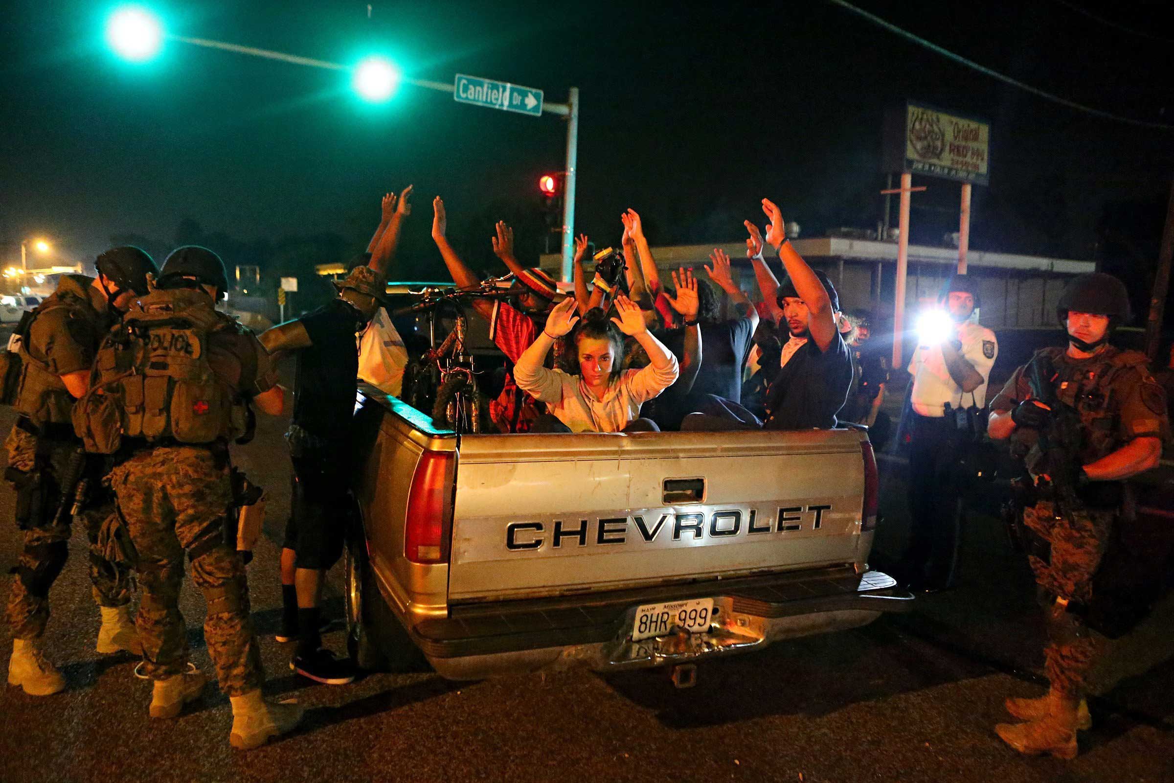 Aug. 19, 2014. Members of the St. Louis County Police tactical team take a truck load of 12 people into custody after they stopped it driving along W. Florissant Road near Canfield Drive. The police found two loaded guns on the people in the truck and removed an unused Molotov cocktail from the truck. Protests and clashes erupted between police and protesters in a Missouri city where racial tensions have boiled over since Ferguson police officer Darren Wilson fatally shot unarmed Black teen Michael Brown on Aug. 9.
