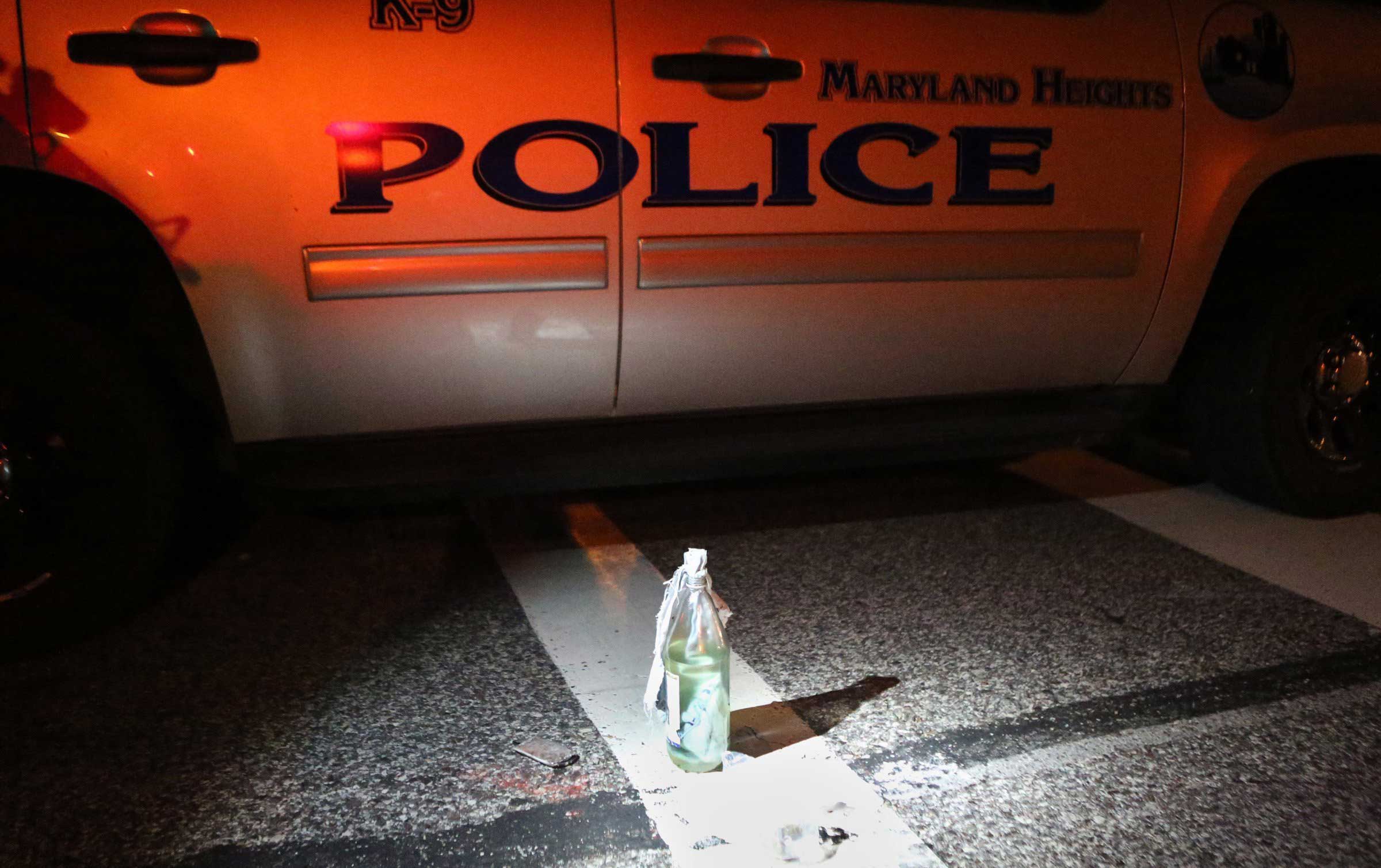 Aug. 19, 2014. A Molotov cocktail sits near a police car after it was removed from a truck carrying 12 people when it was stopped along W. Florissant Avenue near Canfield Drive. The police found two loaded guns on the people in the truck and removed an unused Molotov cocktail from the truck.