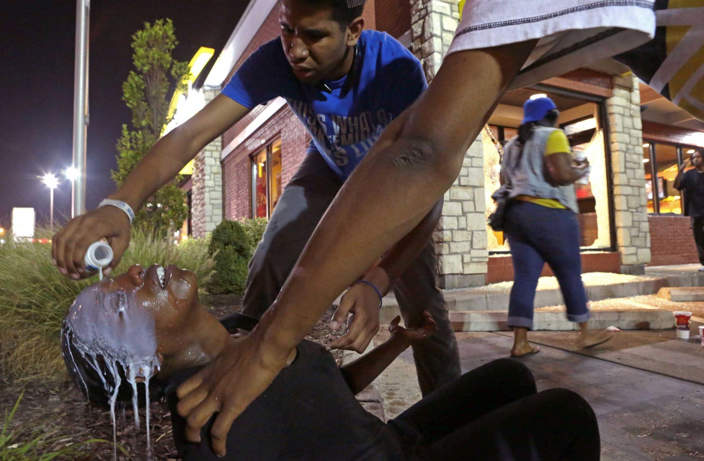 Aug. 17, 2014. Protesters help Cassandra Roberts, who was hit by tear gas on Sunday in Ferguson, Mo. They had broken into the McDonald's to get milk to wash the gas out of her eyes. "We thought it could be a peaceful night," said Roberts, who was marching in Ferguson for the first time. "What the hell is going on in this world?"