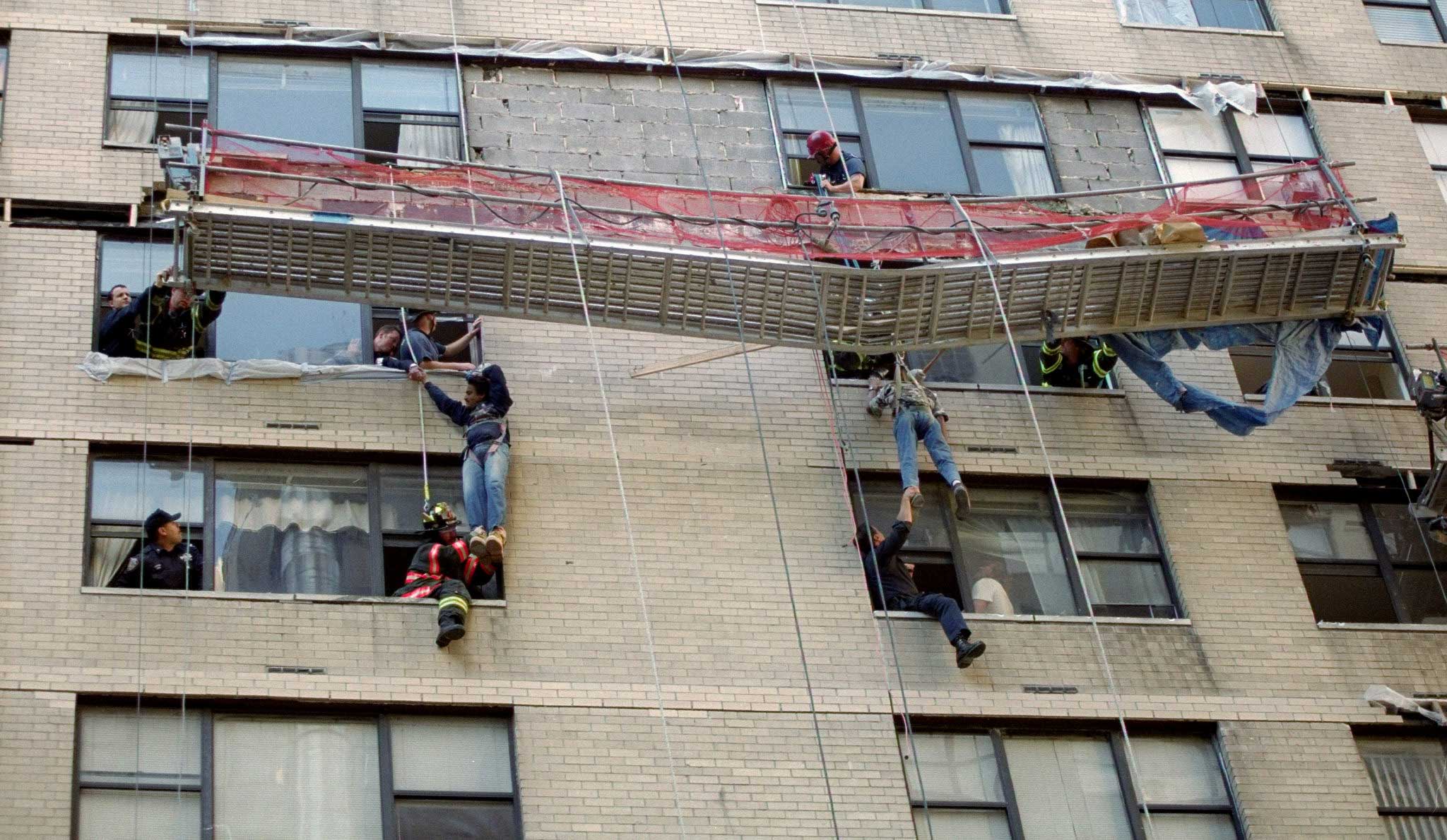 Firefighters rescue two construction workers dangling 8 floors off the ground from a building in Midtown Manhattan in New York city on Oct. 12, 1999.