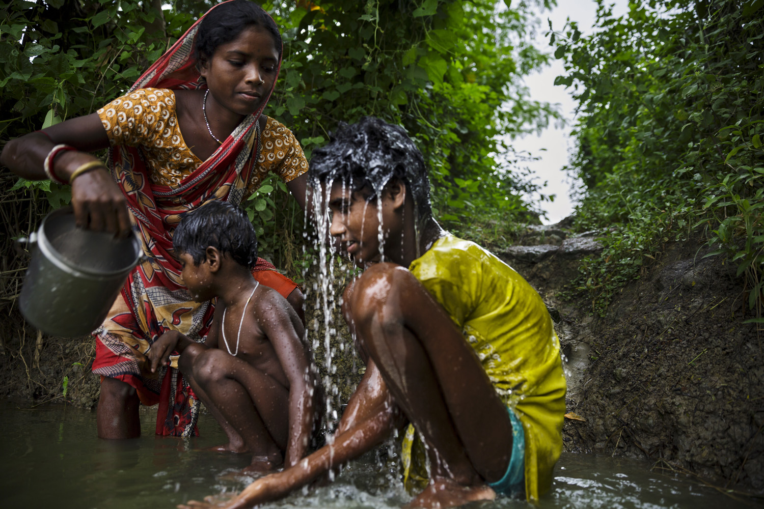 Sonia Singh is bathed by her mother while sister Anita waits her turn, Oct. 21, 2013 in West Bengal, India.