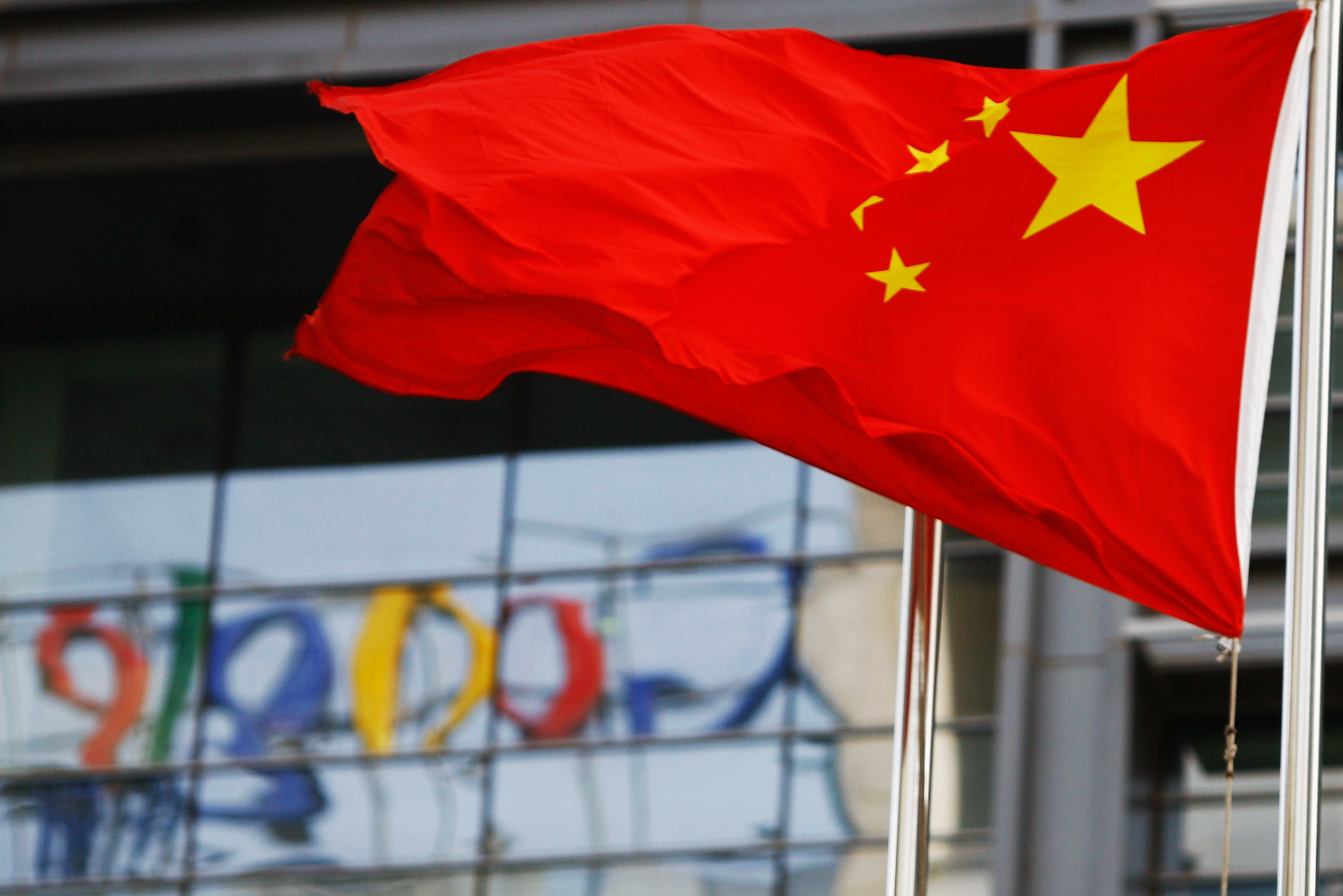 The Google logo is reflected in windows of the company's China head office as the Chinese national flag flies in the wind in Beijing on March 23, 2010. (AFP/Getty Images)