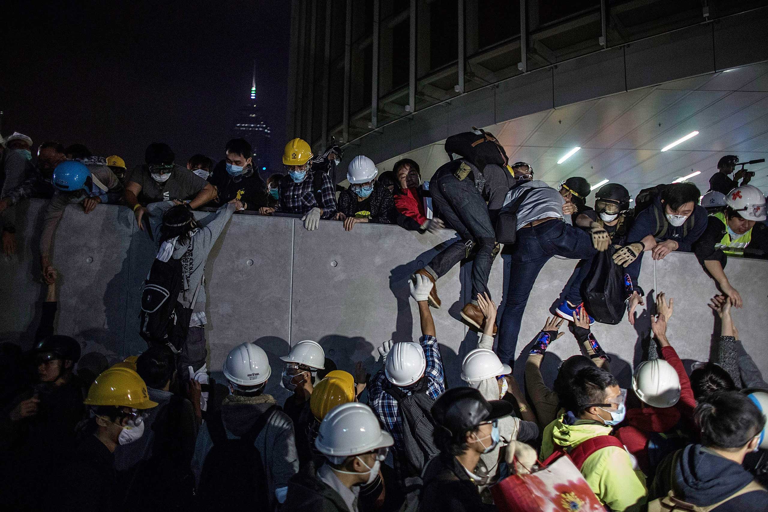 Pro-democracy protesters climb up a wall as police officers disperse them outside the Legislative Council building after clashes with pro-democracy activists on Nov. 19, 2014, in Hong Kong.