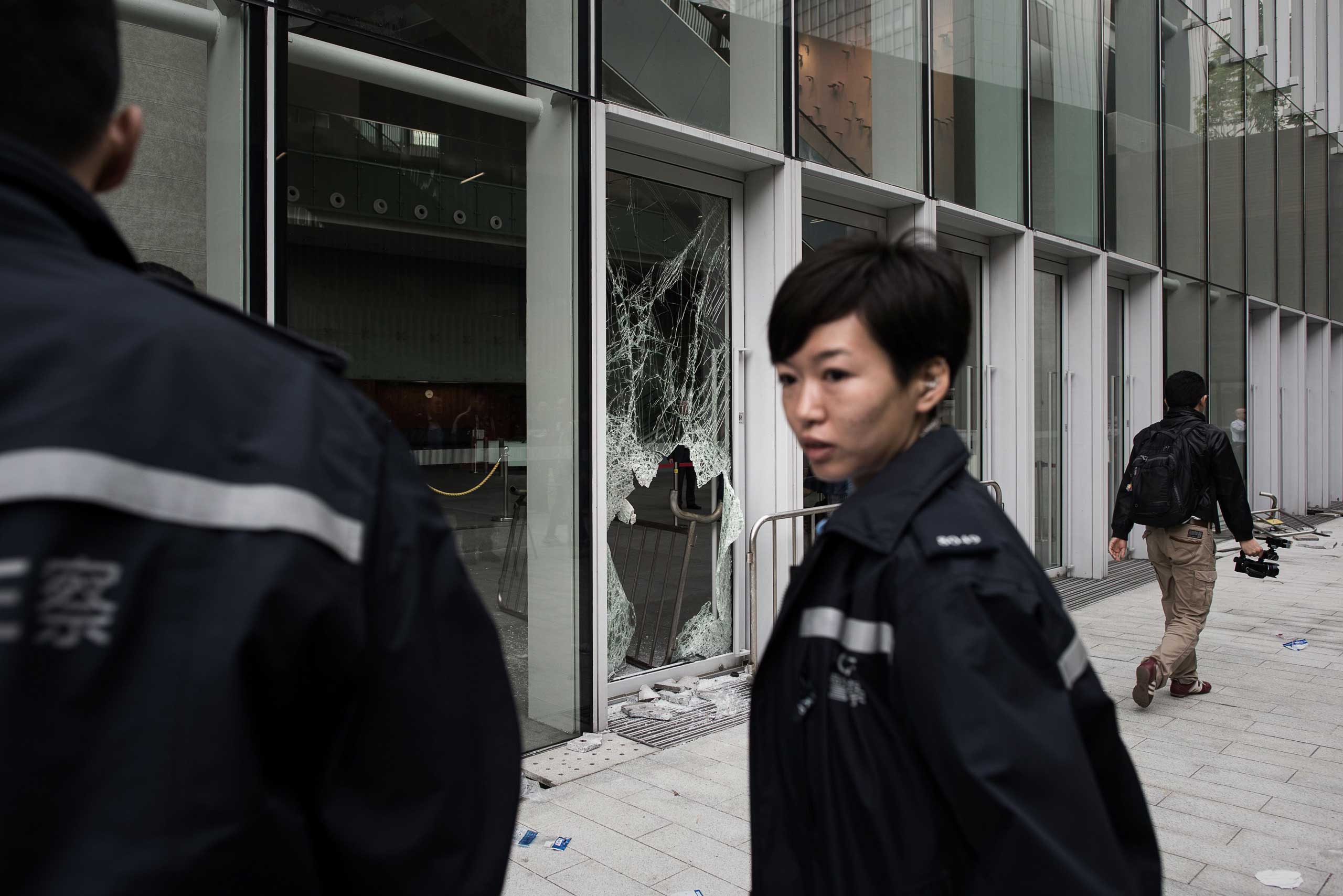 A policewoman stands by a broken window of the government headquarters building in the Admiralty district of Hong Kong on Nov. 19, 2014, after a small group attempted to break into the city's legislature.