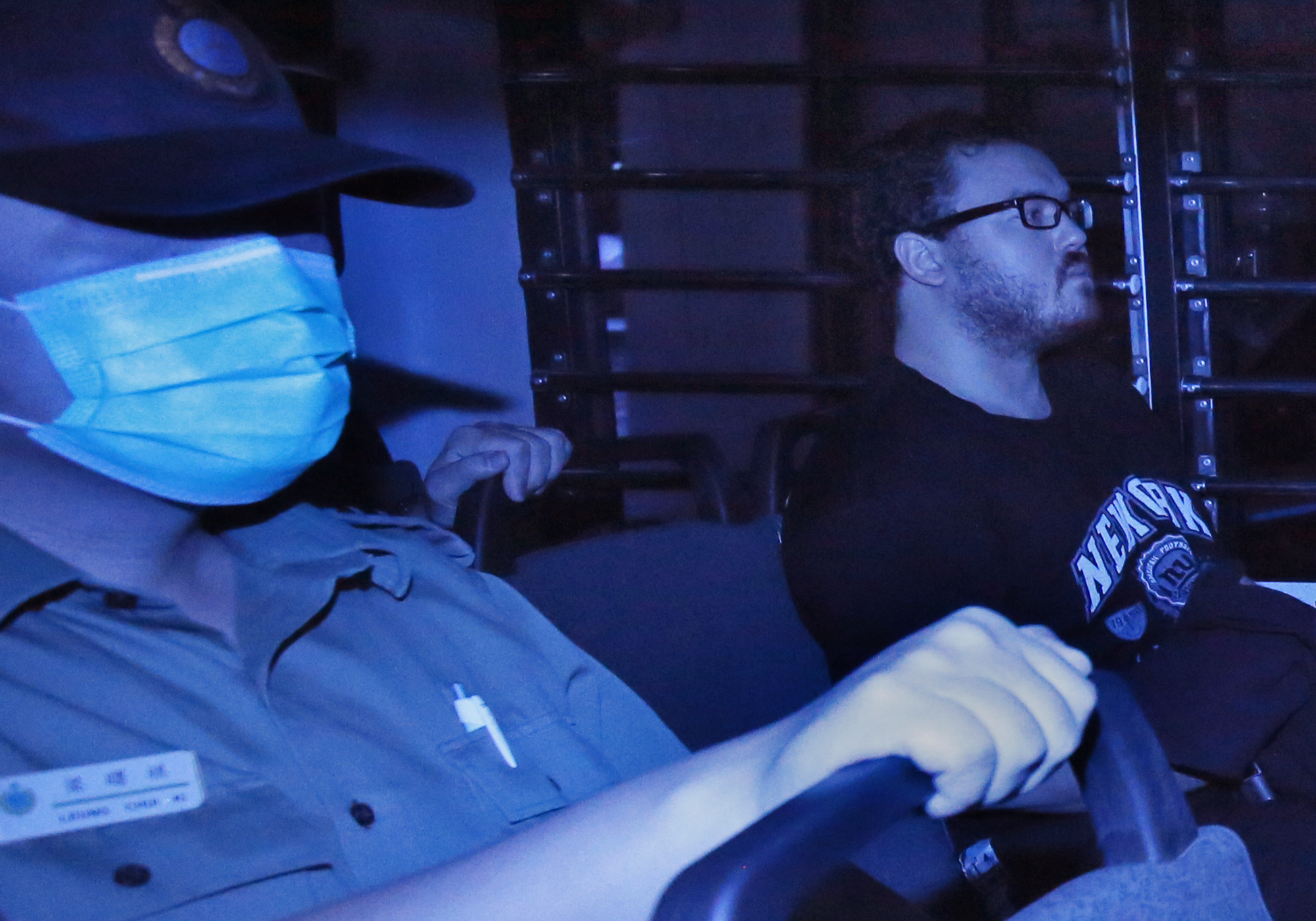 In this photo taken through tinted glass, Rurik George Caton Jutting, right, a 29-year-old  British banker, is escorted by Correctional Services officers in a prison bus arriving at a court in Hong Kong on Nov. 10, 2014 (Vincent Yu—AP)