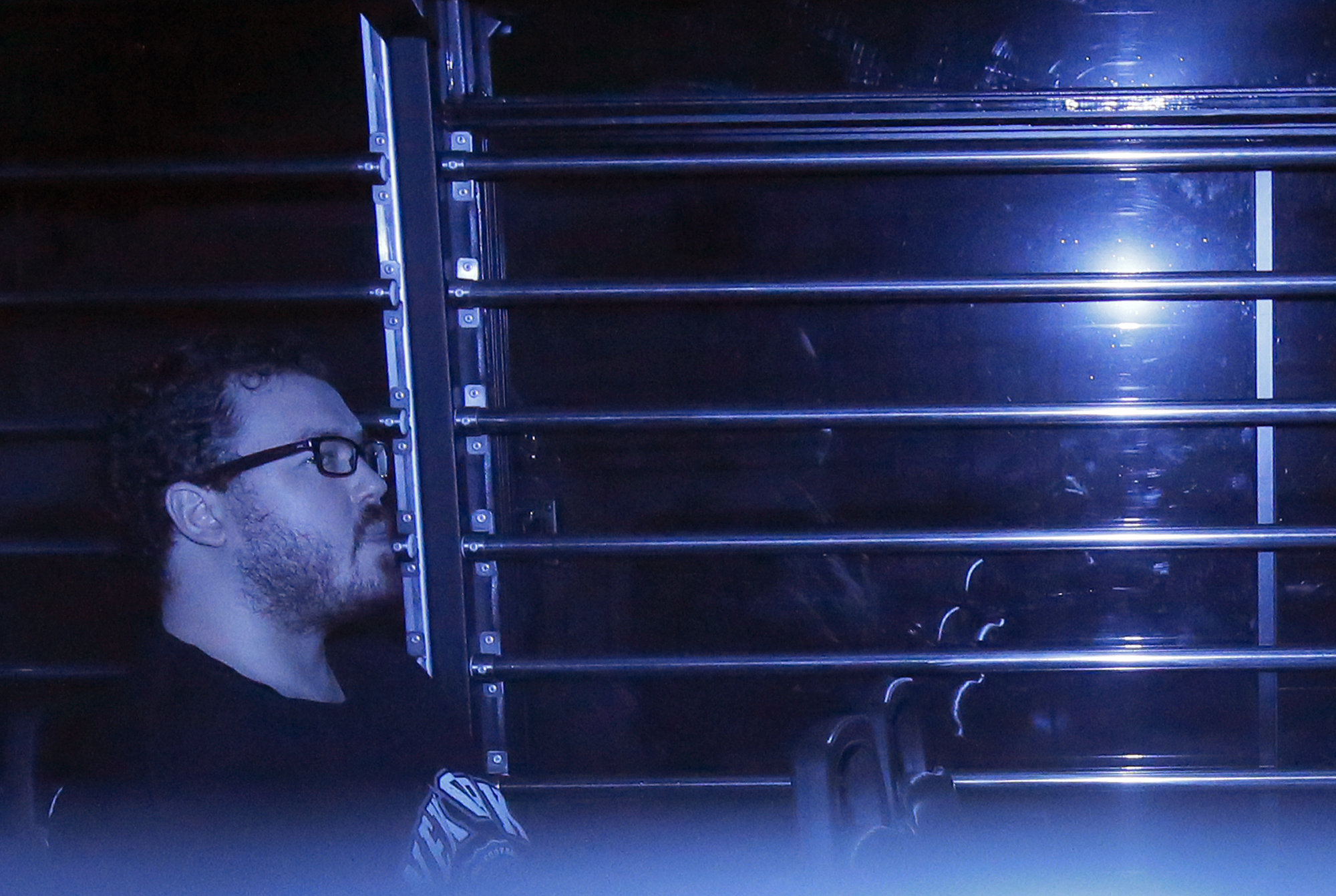 In this photo taken through tinted glass, Rurik George Caton Jutting, a 29-year-old British banker, sits in a prison bus arriving at a court in Hong Kong on Nov. 10, 2014 (Vincent Yu—AP)