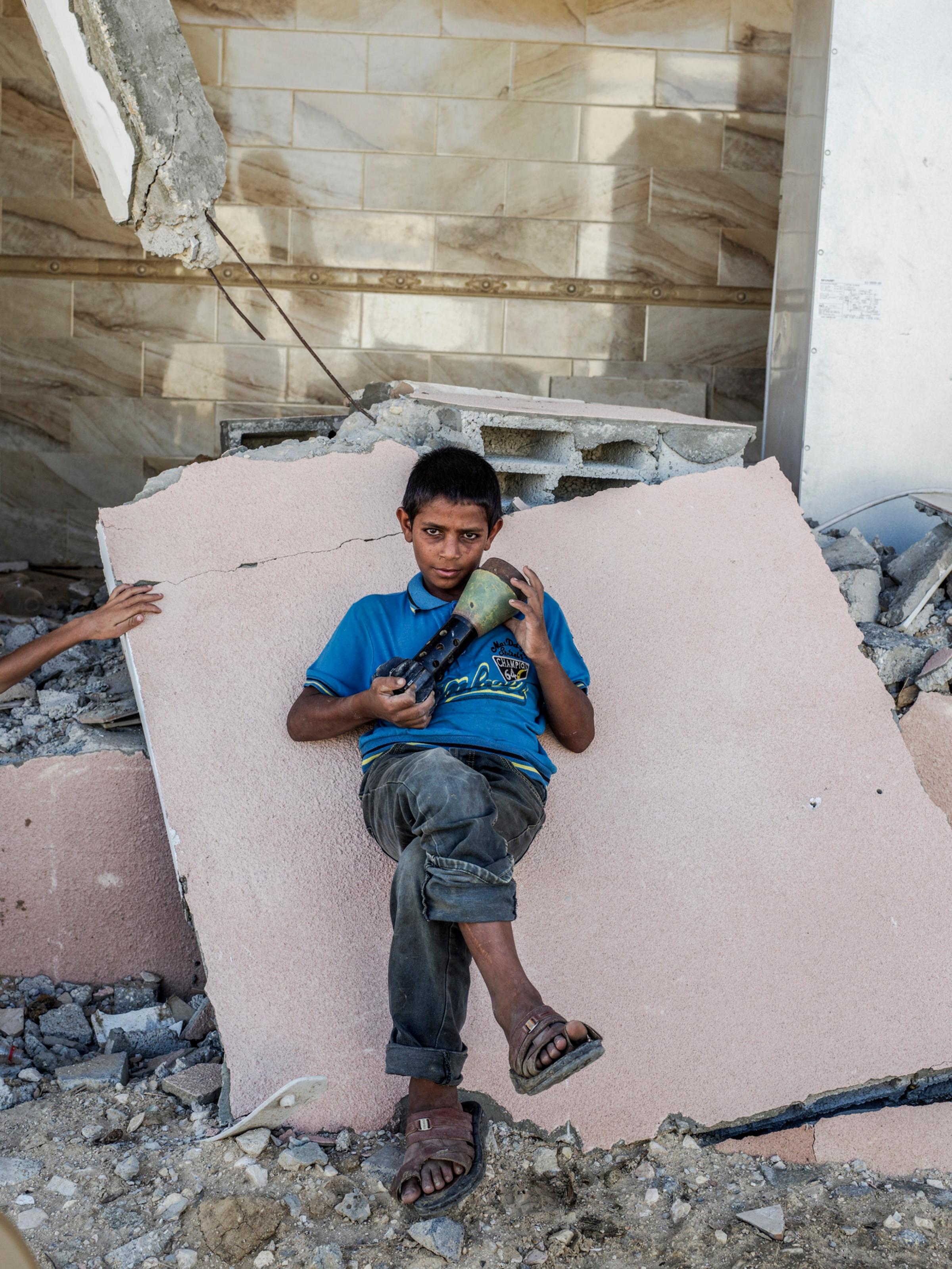 2014.  Gaza.  Palestine. A child with an Israeli mortar shell in a neighborhood destroyed near Rafah in southern Gaza.  Operation Protective Edge lasted from 8 July 2014 – 26 August 2014, killing 2,189 Palestinians of which 1,486 are believed to be civilians. 66 Israeli soldiers and 6 civilians were killed.  It's estimated that 4,564 rockets were fired at Israel by Palestinian militants.