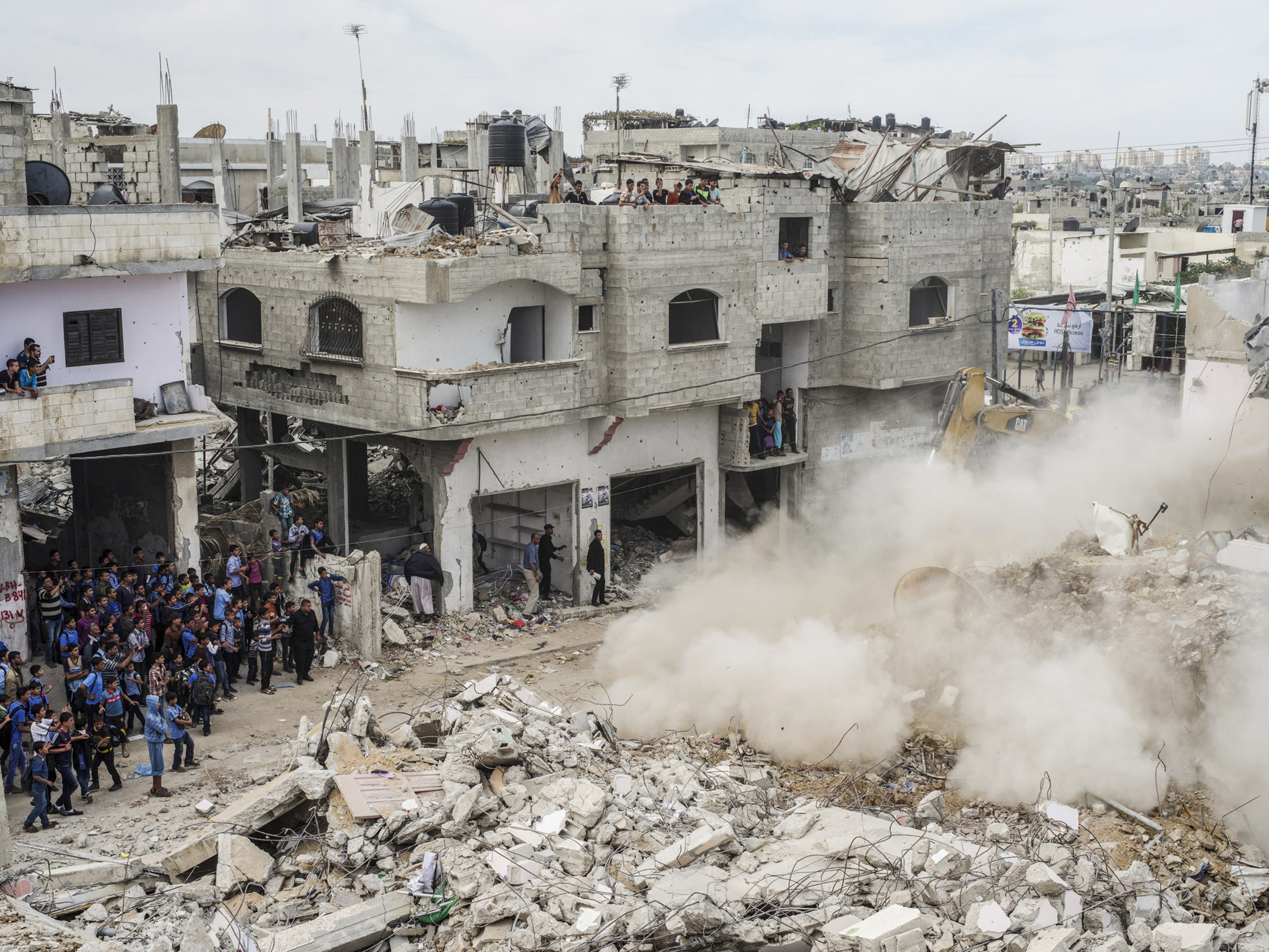 A crowd watches as a destroyed home is knocked down in Beit Hanoun, Gaza.