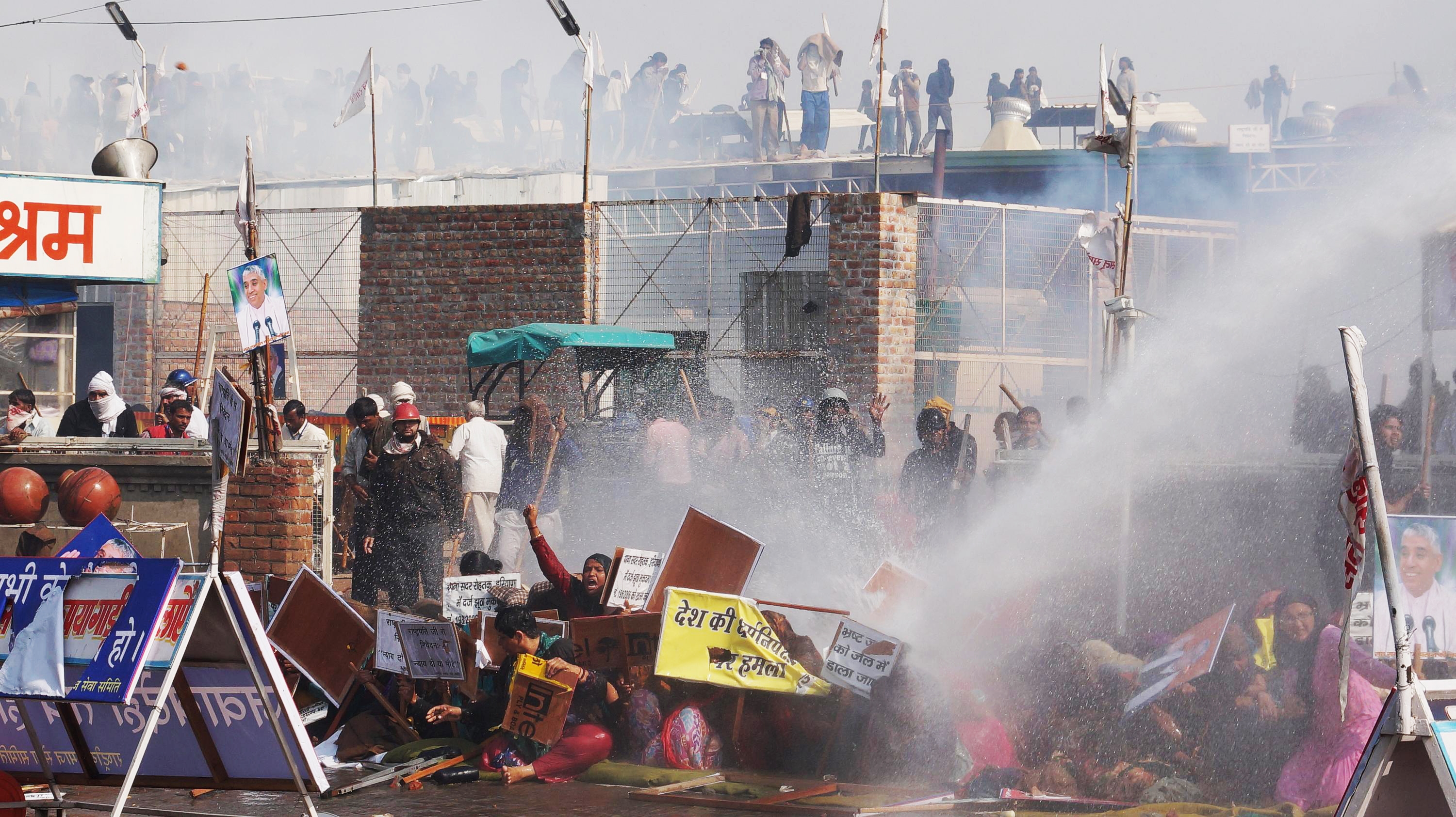 Supporters try to resist police water cannon as police storm the ashram of controversial Indian guru Sant Rampal, in search of him at Hisar in Haryana state, India, Tuesday, Nov.18, 2014. (Bansilal Basniwal—AP)