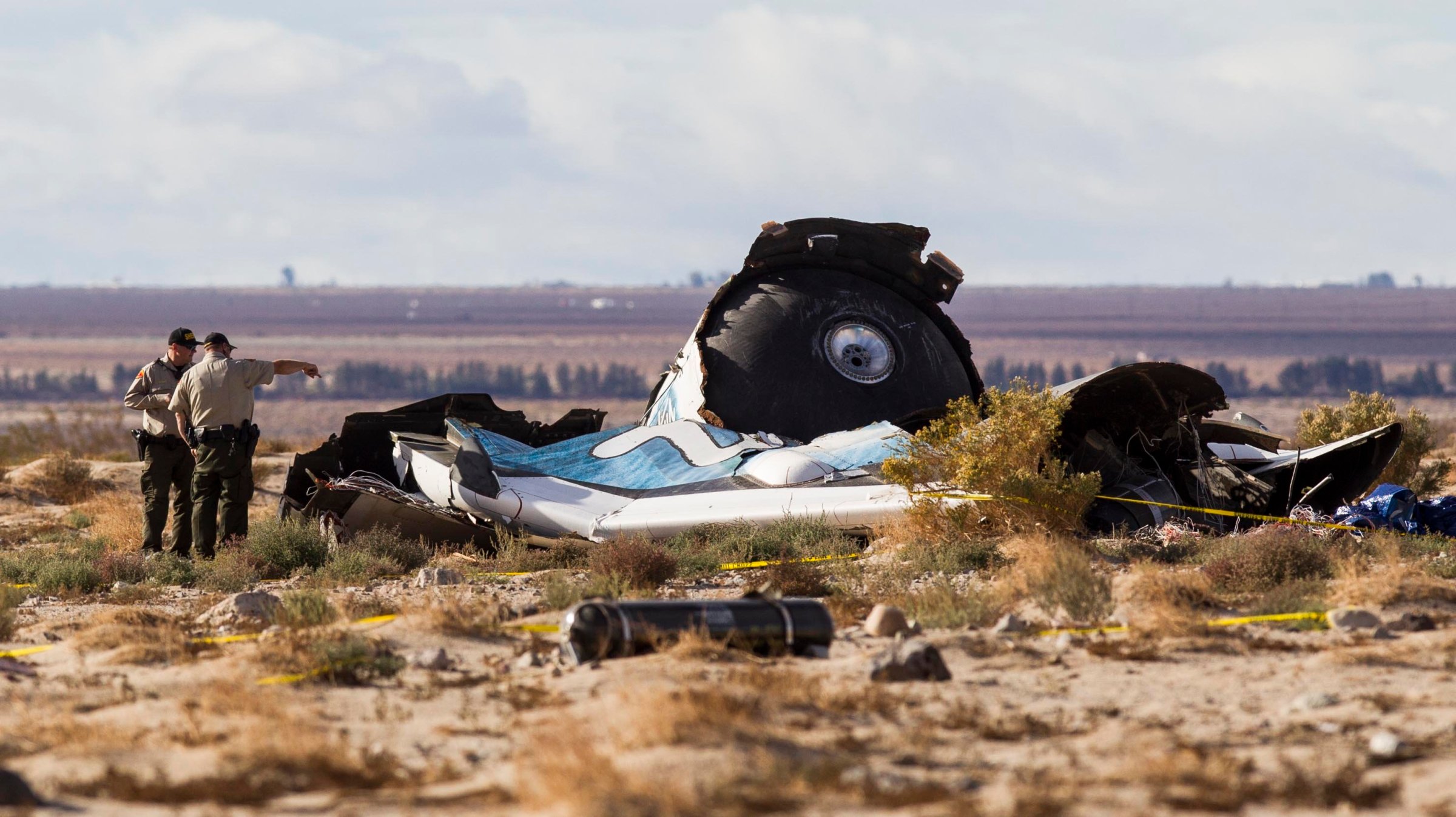 Law enforcement officers take a closer look at the wreckage near the site where a Virgin Galactic space tourism rocket, SpaceShipTwo, exploded and crashed in Mojave, Calif. on Nov 1, 2014.