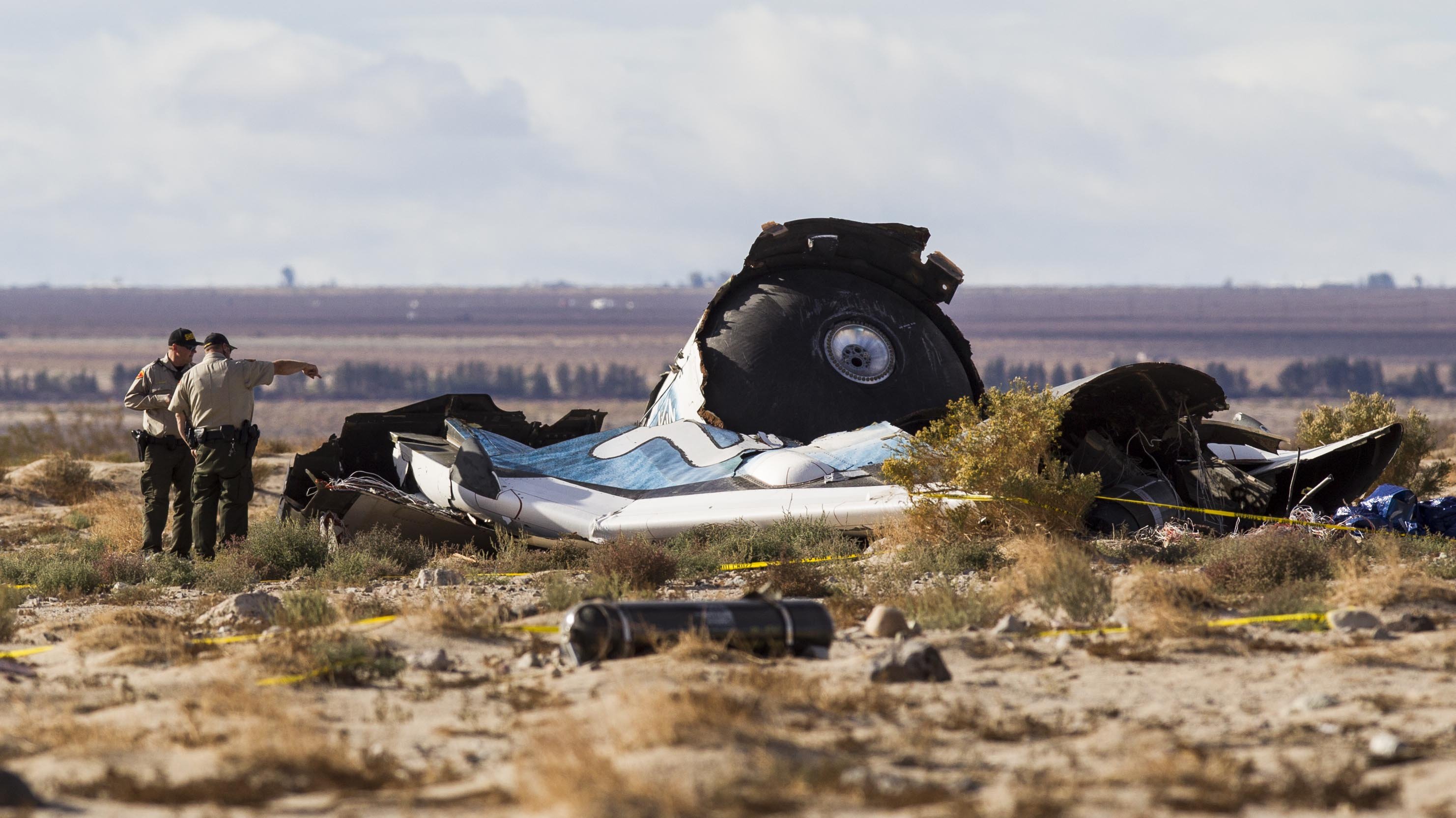 Law enforcement officers take a closer look at the wreckage near the site where a Virgin Galactic space tourism rocket, SpaceShipTwo, exploded and crashed in Mojave, Calif. on Nov 1, 2014. (Ringo H.W. Chiu—AP)