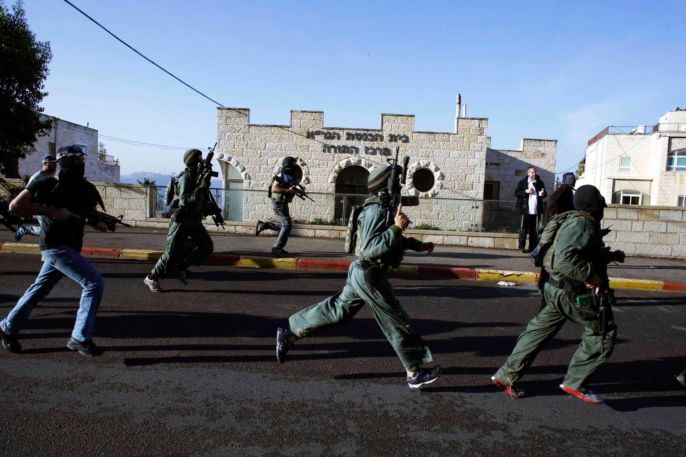 Israeli security personnel run next to a synagogue, where a suspected Palestinian attack took place, in Jerusalem, Nov. 18, 2014.