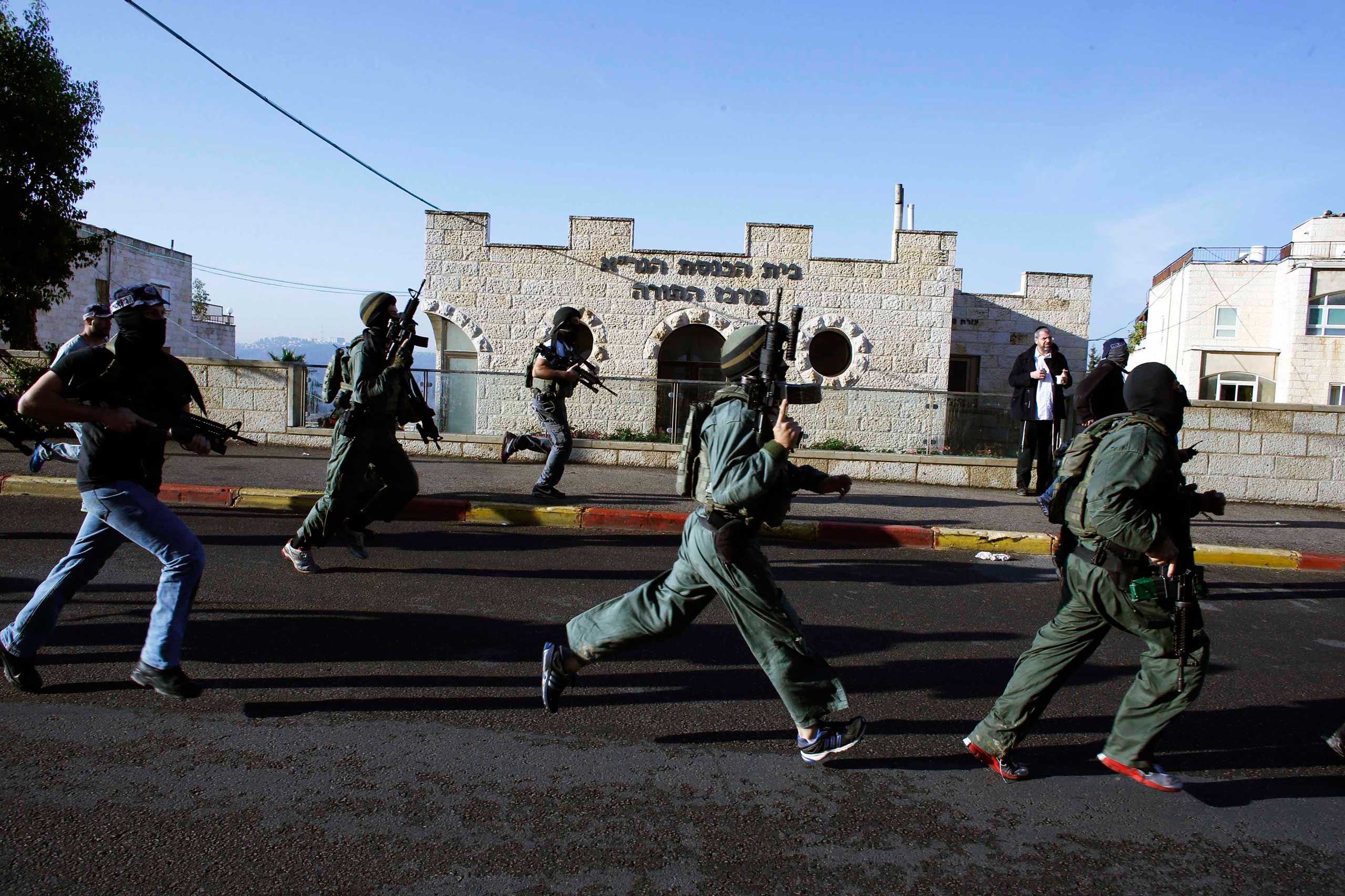 Israeli security personnel run next to a synagogue, where a suspected Palestinian attack took place, in Jerusalem