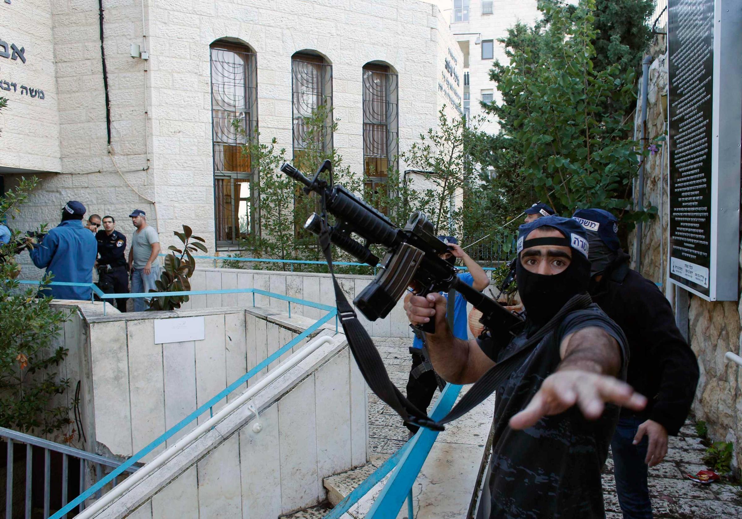 An Israeli police officer gestures as he holds a weapon near the scene of an attack at a Jerusalem synagogue, Nov. 18, 2014.