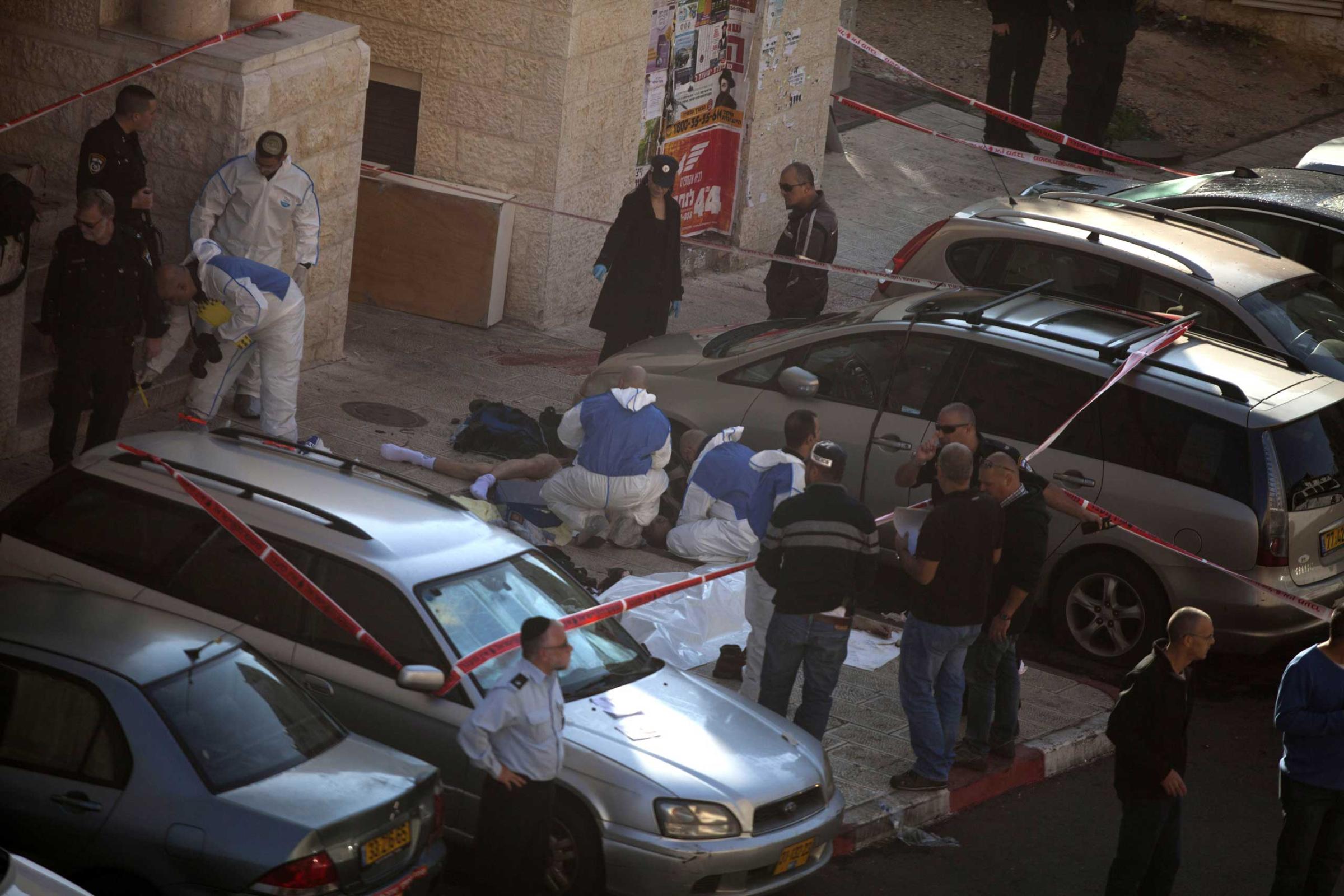 Israeli police crime scene investigators stand near bodies of suspected attackers outside a synagogue on Nov. 18, 2014 in Jerusalem.