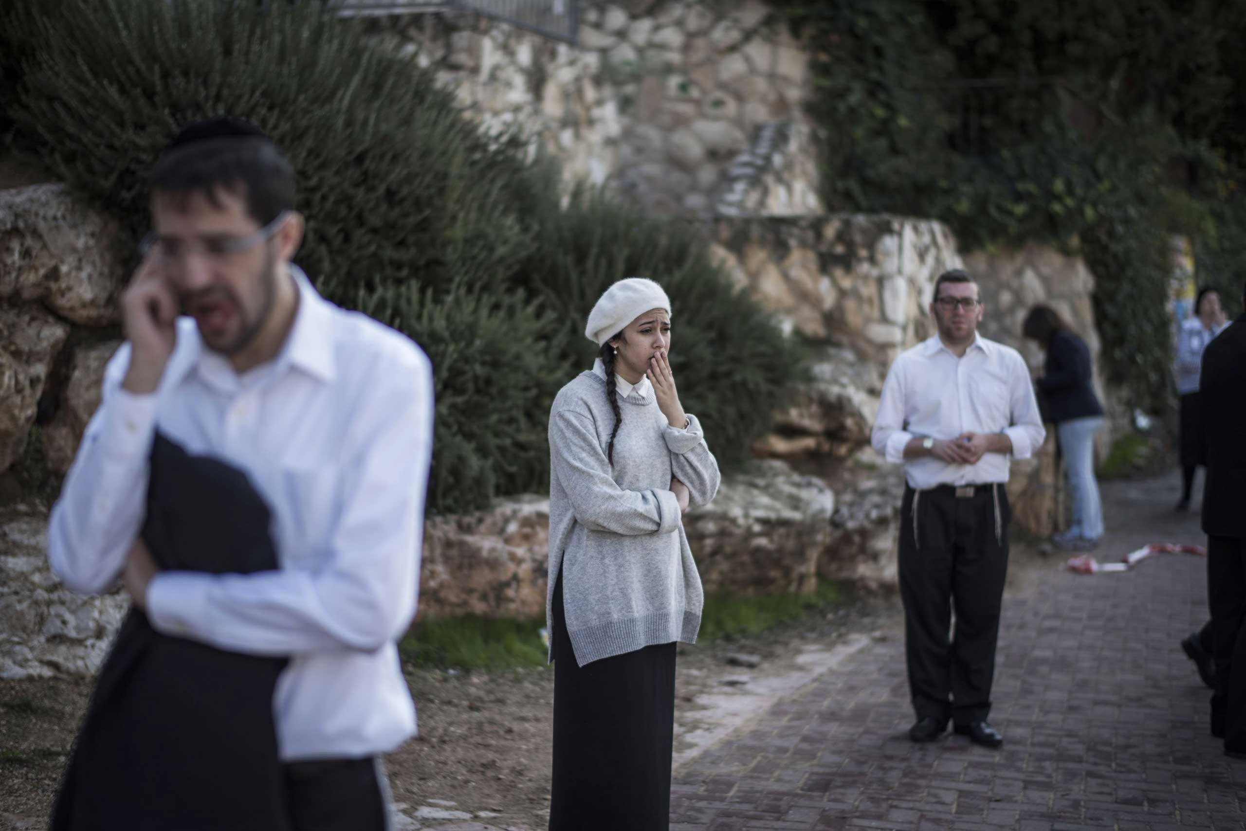 People react as they stand outside a synagogue in Jerusalem on Nov. 18, 2014.