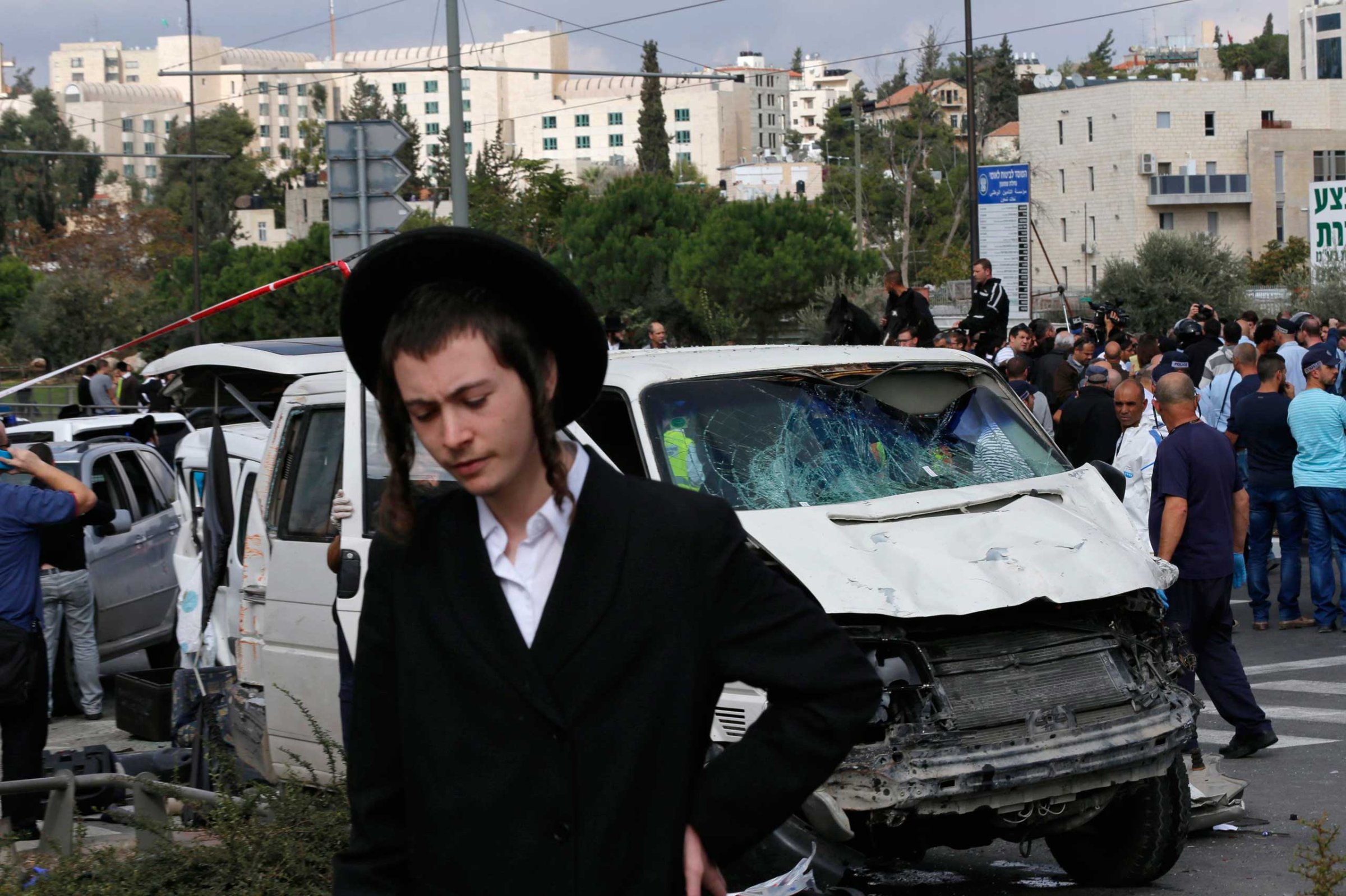 An ultra-Orthodox youth stands in front of the vehicle of a Palestinian motorist who rammed into pedestrians at the scene of an attack in Jerusalem, Nov. 5, 2014.