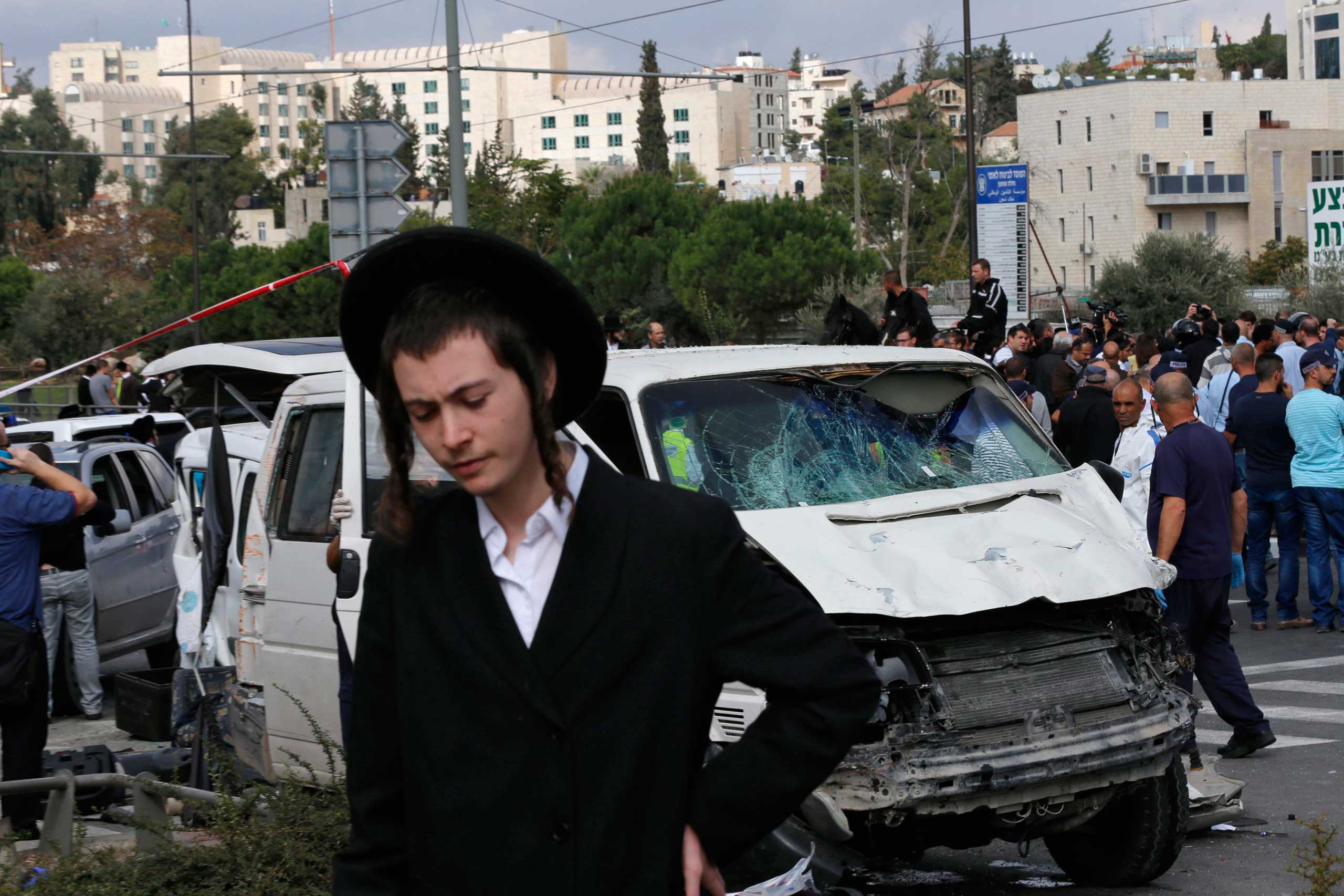 An ultra-Orthodox youth stands in front of the vehicle of a Palestinian motorist who rammed into pedestrians at the scene of an attack in Jerusalem, Nov. 5, 2014. (Ammar Awad—Reuters)