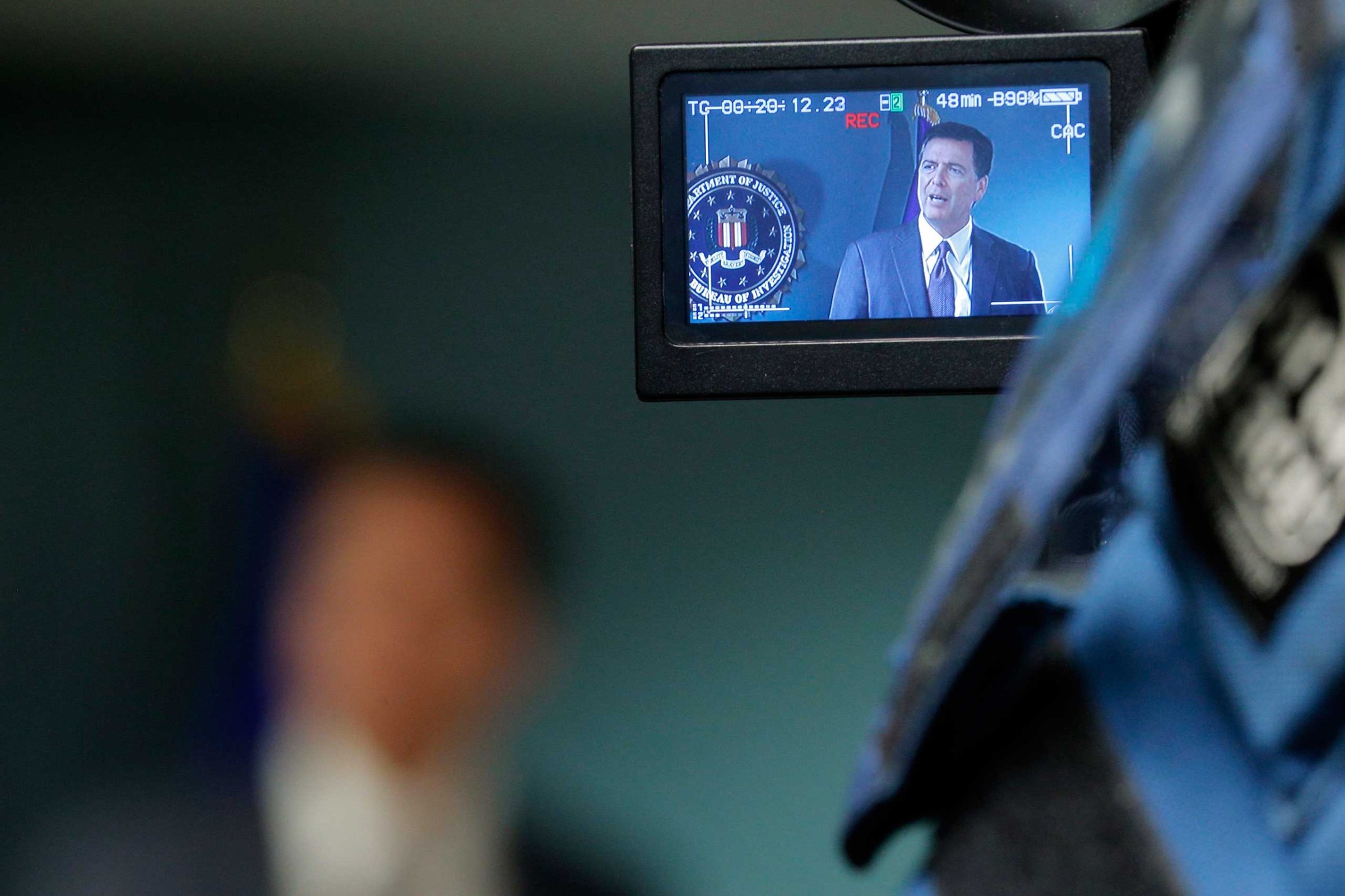 Television cameras record FBI Director James Comey as he answers questions from reporters during a news conference at the FBI office in Boston, Mass., Nov. 18, 2014.