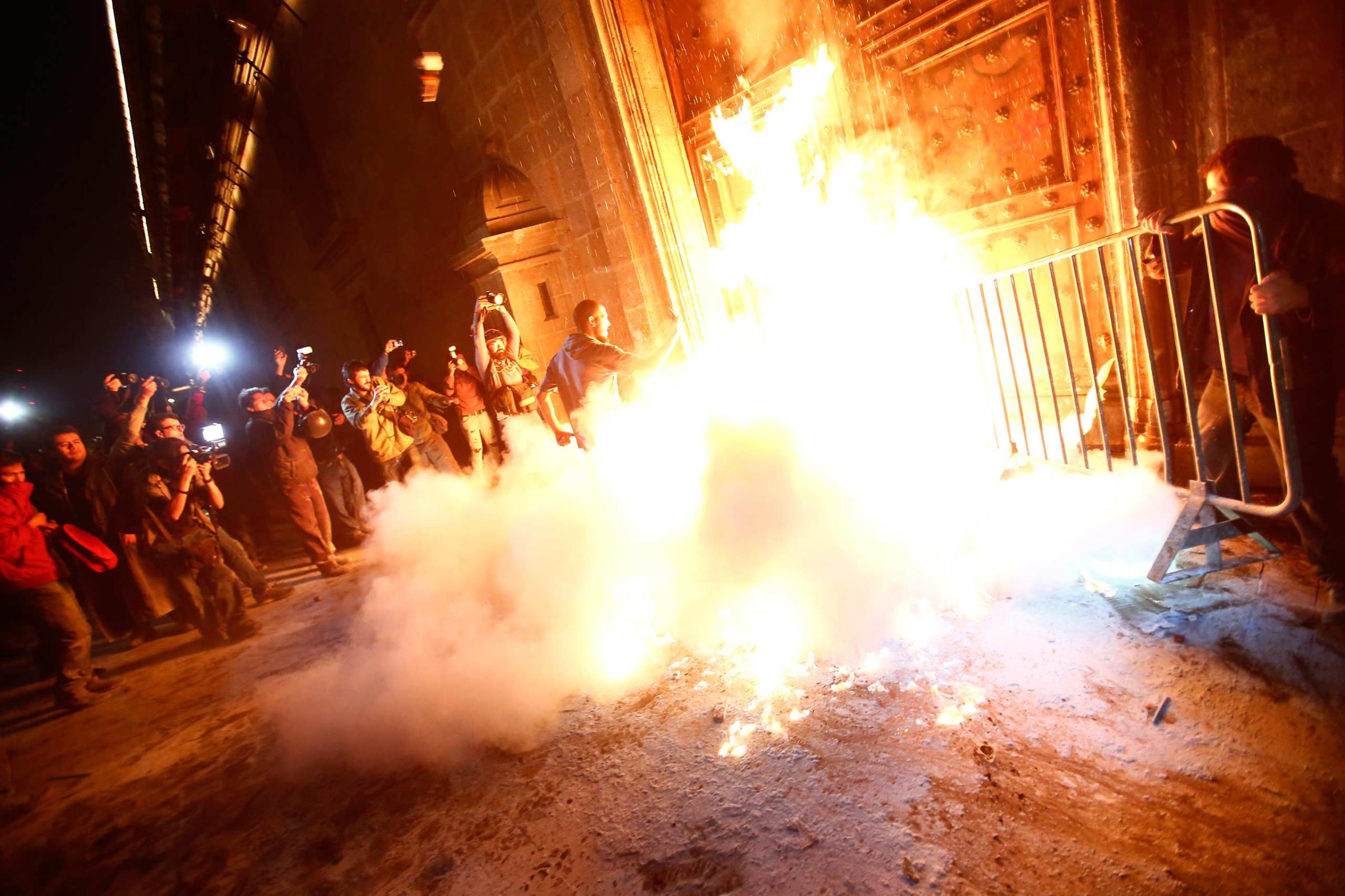 Protesters set fire to the wooden door of Mexican President Pena Nieto's ceremonial palace in Mexico City