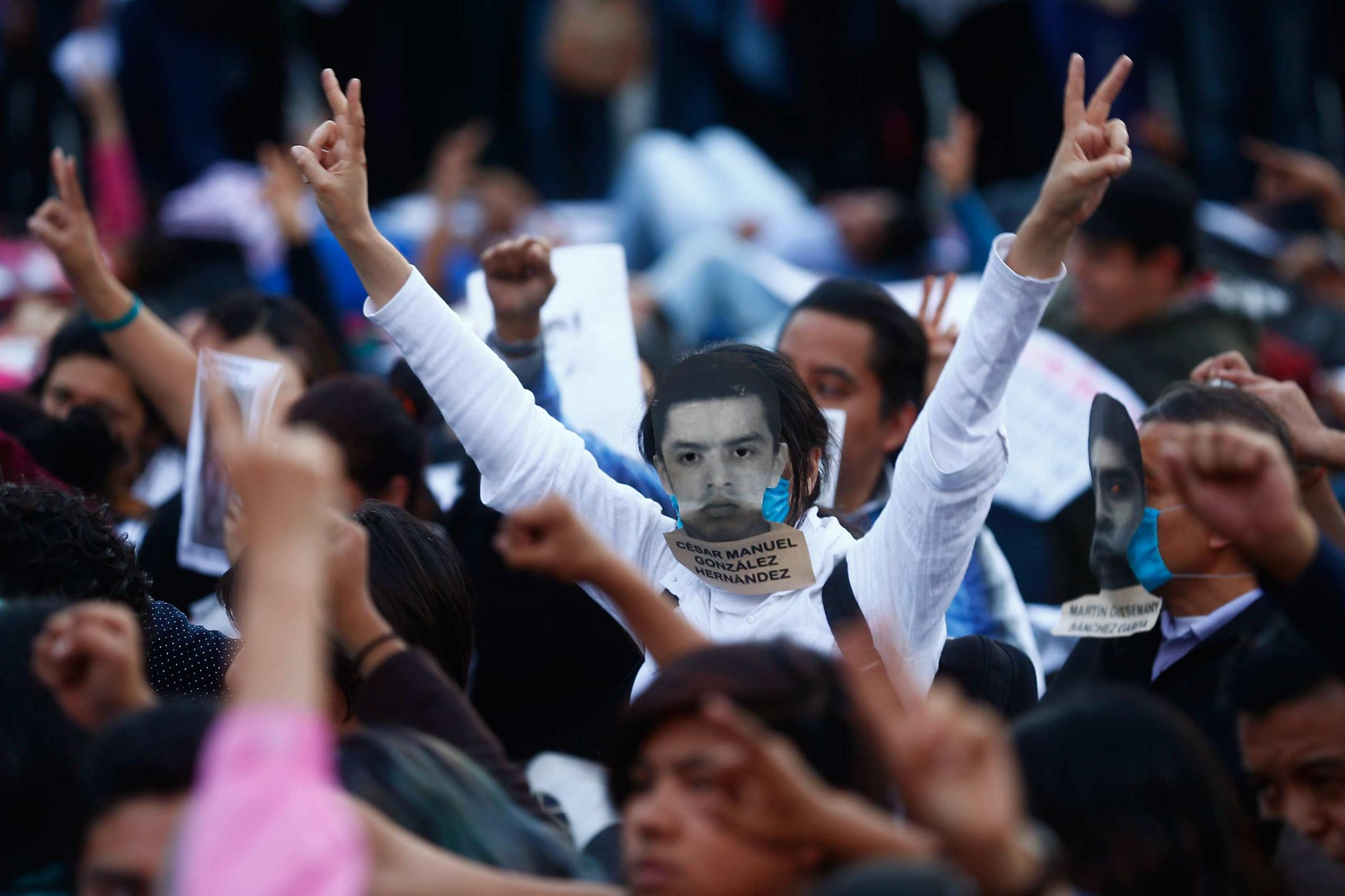Demonstrator whose face is covered with a picture of a missing student gestures during a protest in support of the missing Ayotzinapa Teacher Training College Raul Isidro Burgos students at Zocalo square in Mexico City
