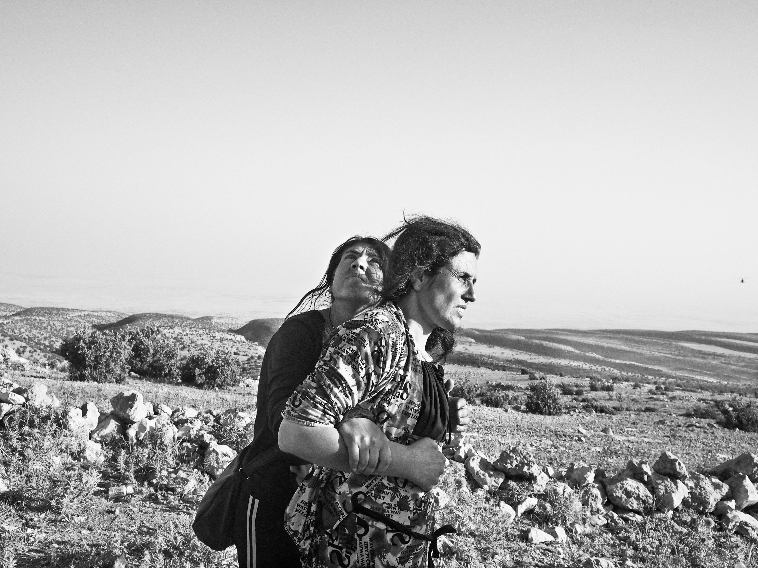 Yezidi women stranded in the Sinjar Mountains wait for the arrival of a rescue helicopter. Iraq. Aug. 12, 2014.