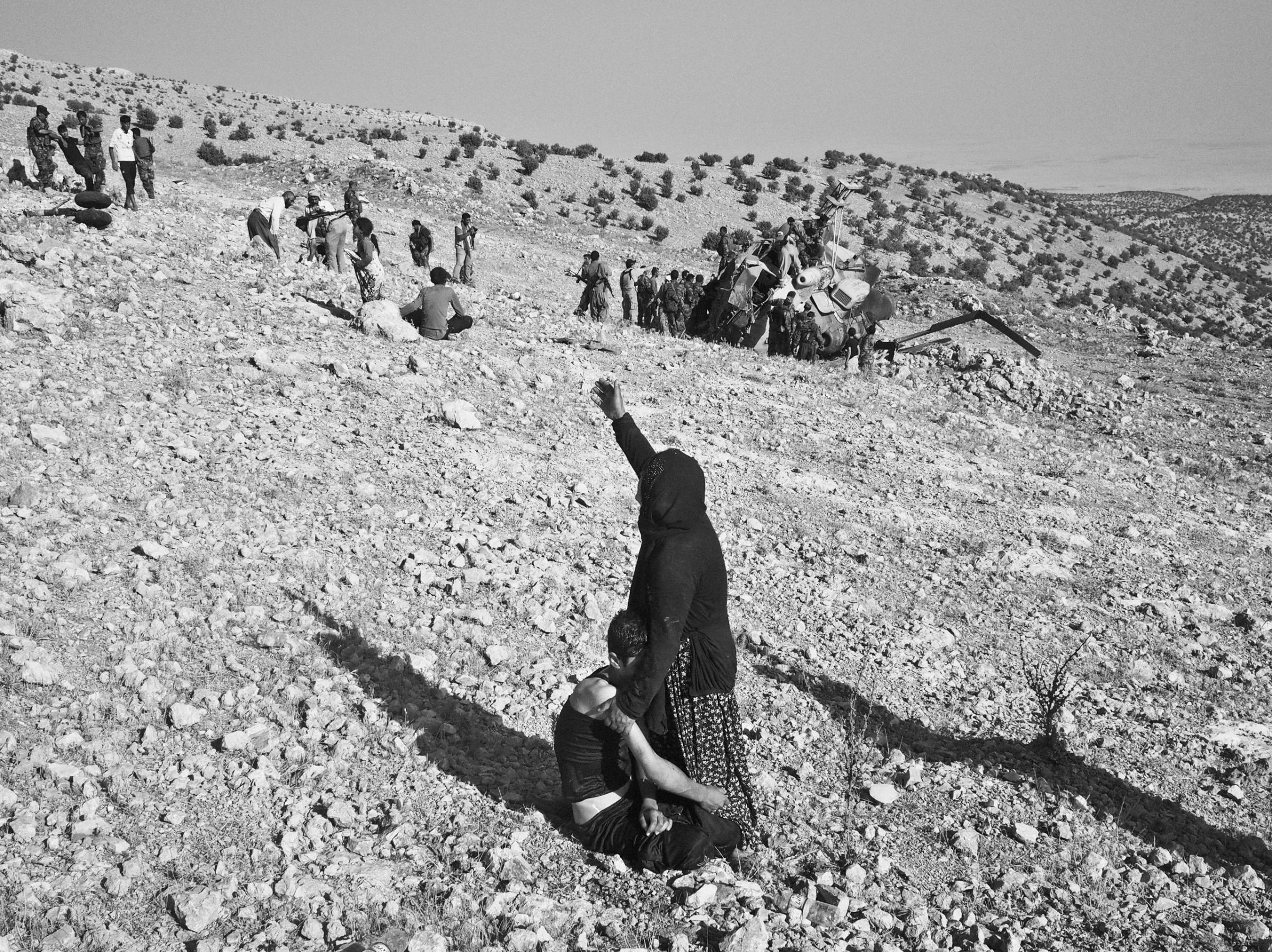 A woman cries for help as she holds on to her wounded son at the crash site of an Iraqi air force helicopter. Sinjar Mountains, Iraq. Aug. 12, 2014.