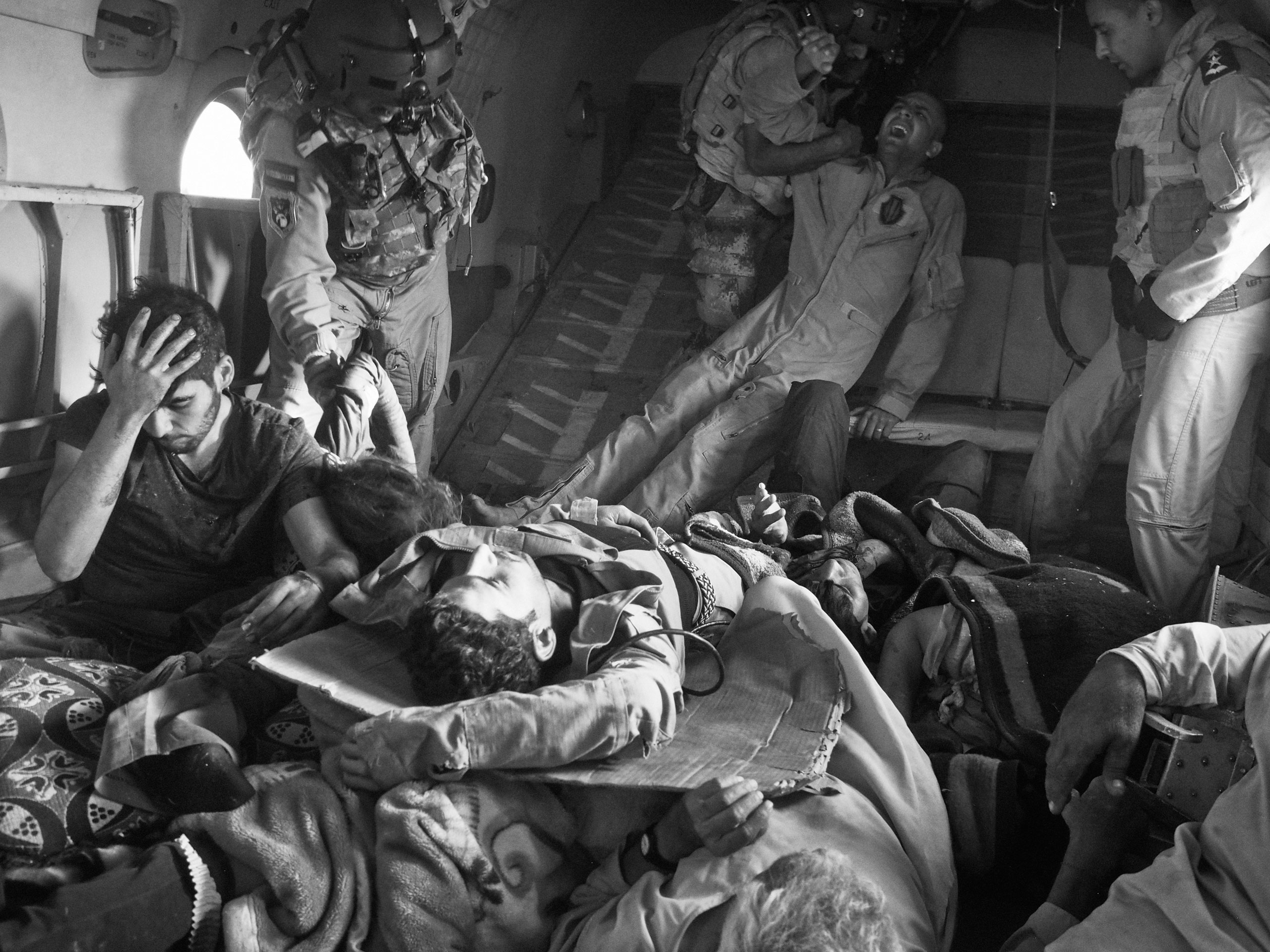 Survivors of the Sinjar crash, including Yezidis and Kurdish and Iraqi military personnel, are loaded onto a second rescue helicopter bound for Kurdish territory. The pilot killed in the crash lies under the wounded. Aug. 12, 2014.