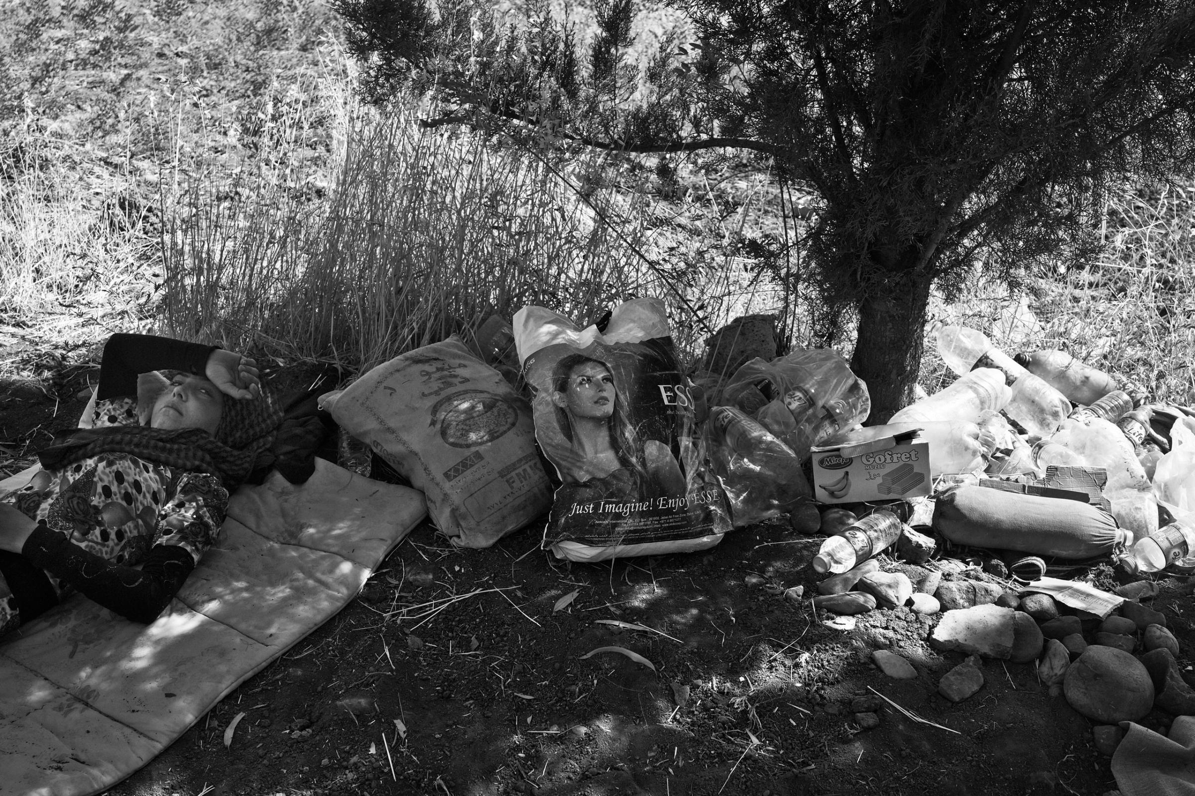 Nada, a 12-year-old Yezidi girl from Sinjar, rests under a tree next to her family's belongings shortly after crossing into Kurdish-controlled Dohuk Province. Fishkhabur, Iraq. Aug. 11, 2014.