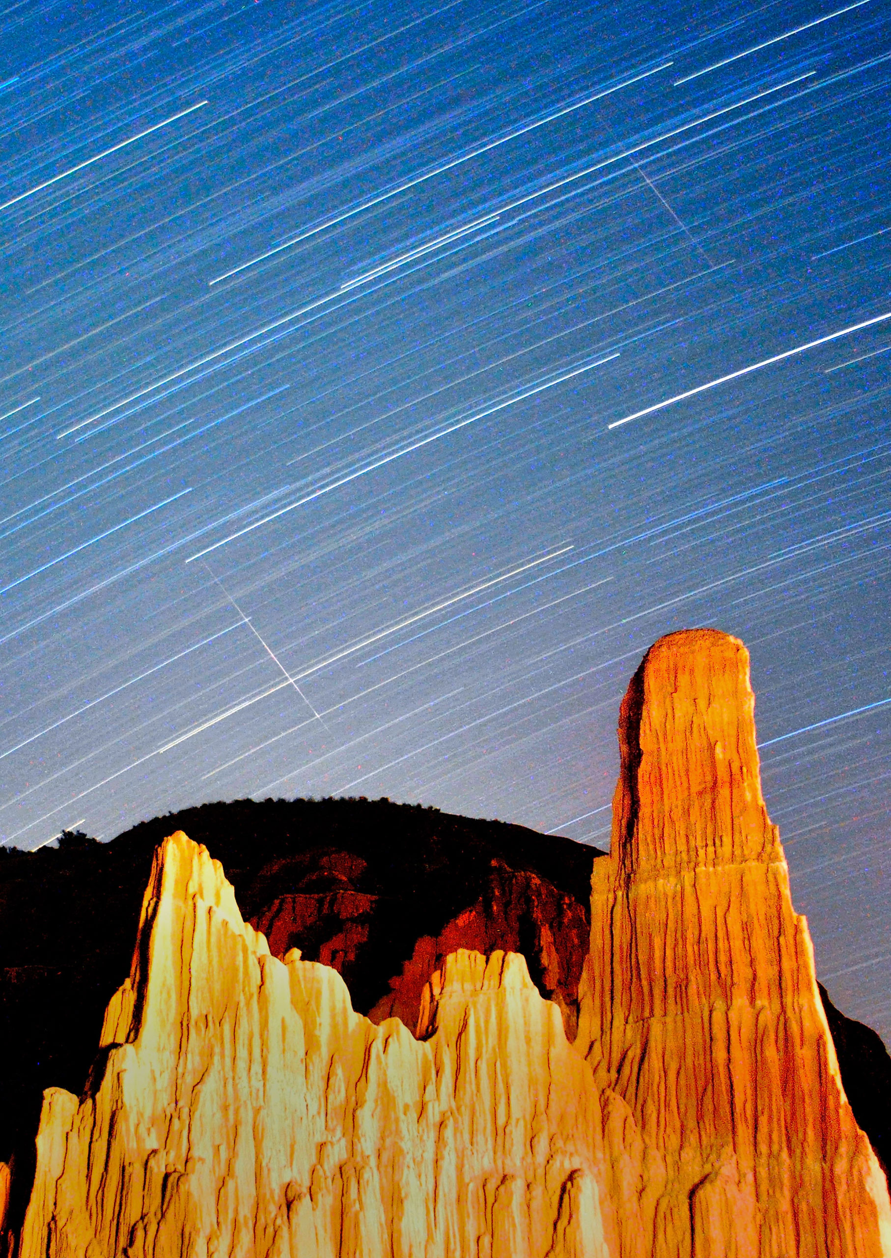 Perseid meteors streak across the sky through star trails over Cathedral Gorge State Park in this long exposure on Aug. 12, 2013.