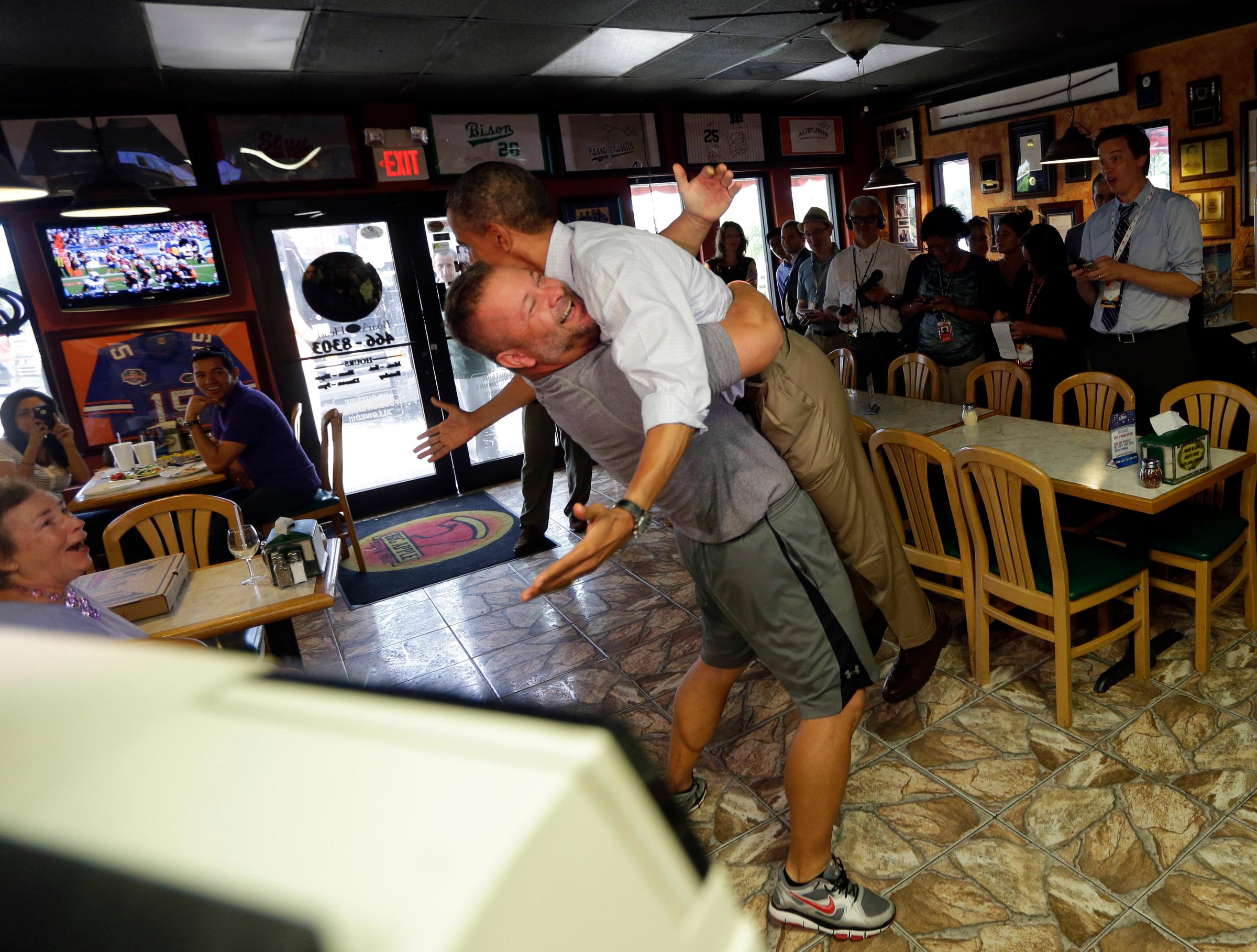 President Barack Obama, right, is picked-up and lifted off the ground by Scott Van Duzer, left, owner of Big Apple Pizza and Pasta Italian Restaurant during an unannounced stop, Sunday, Sept. 9, 2012, in Ft. Pierce, Fla. (AP Photo/Pablo Martinez Monsivais)